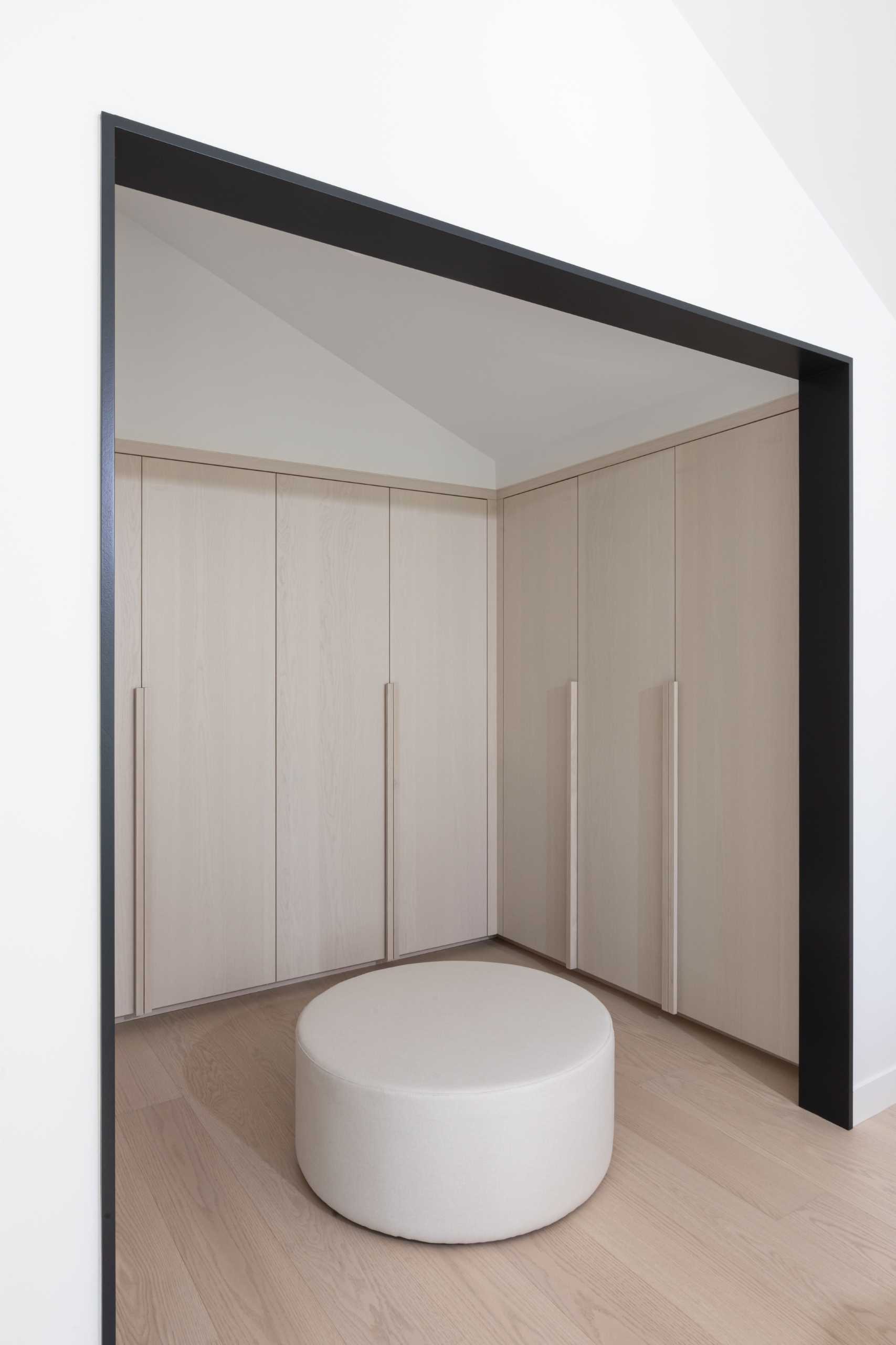 A modern bedroom with an open walk-in closet with light wood cabinets.