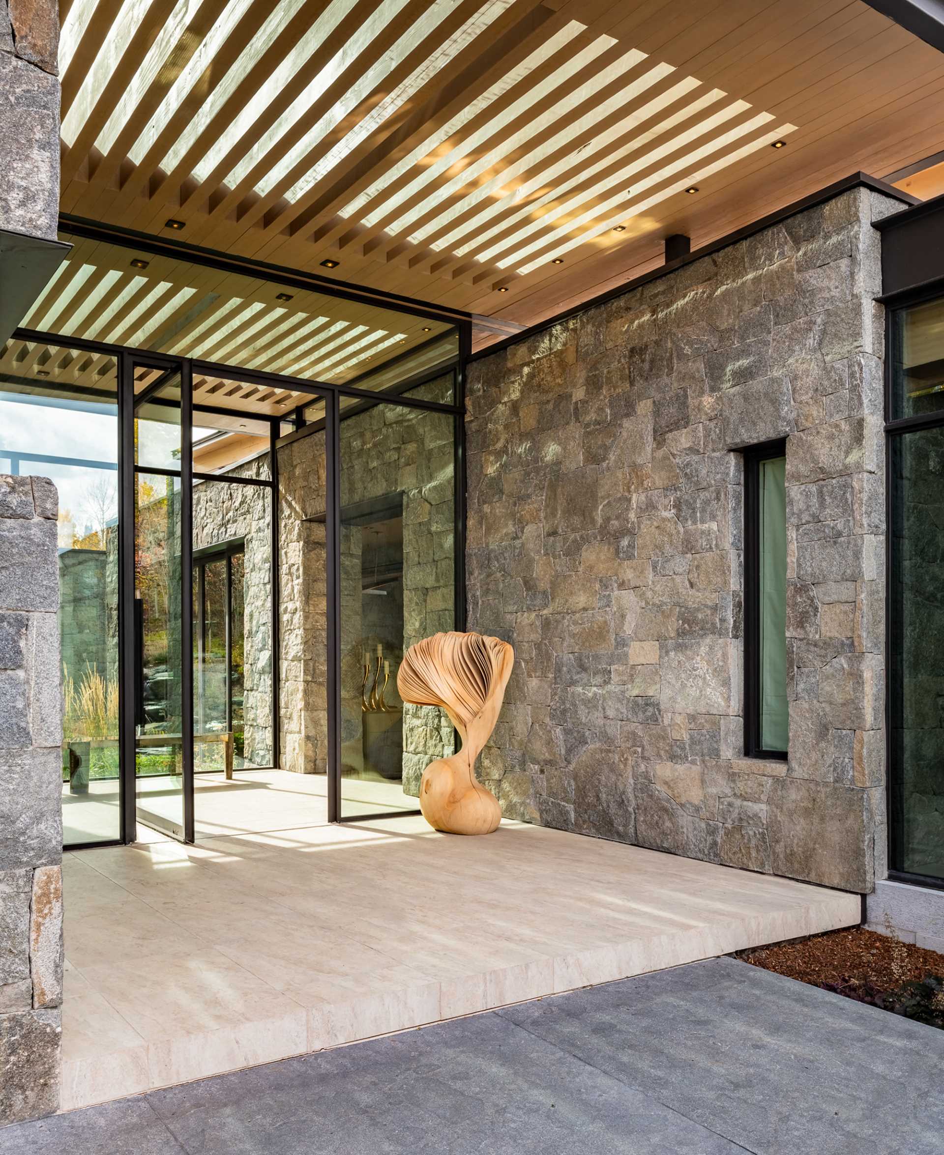 The entryway of this contemporary mountain home showcases stone, wood, steel, and glass.