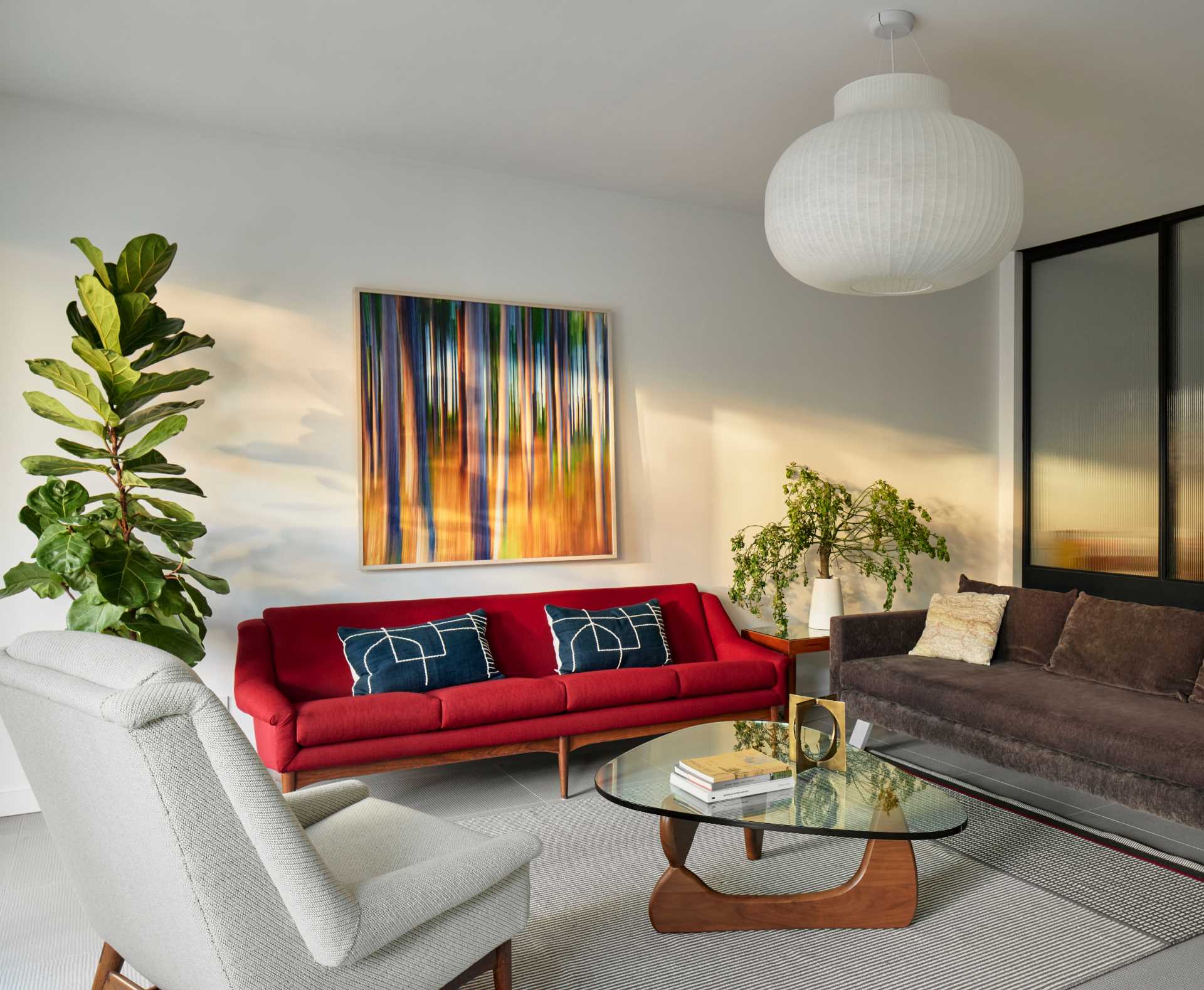 A modern basement living room with a bright red couch and colourful artwork.