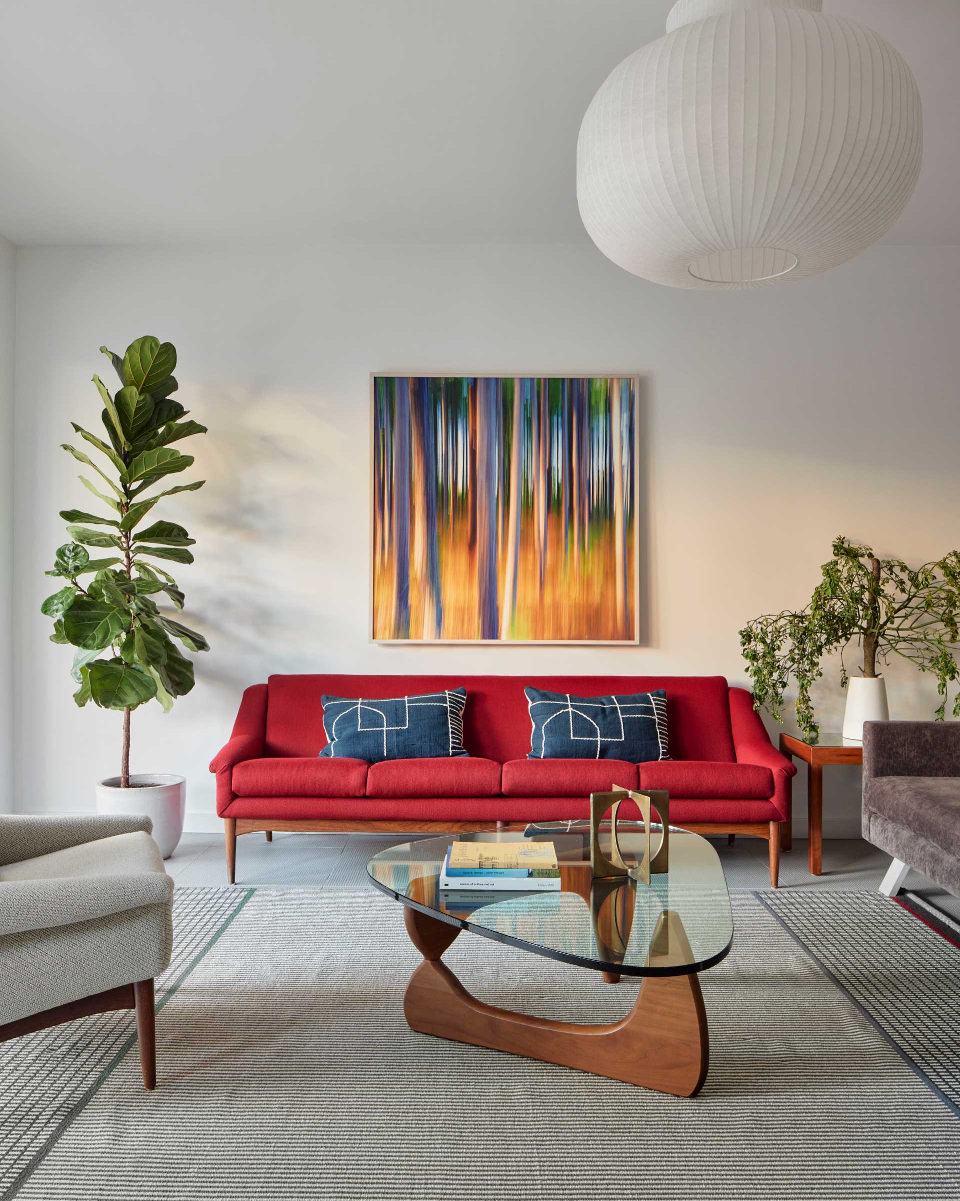 A modern basement living room with a bright red couch and colourful artwork.