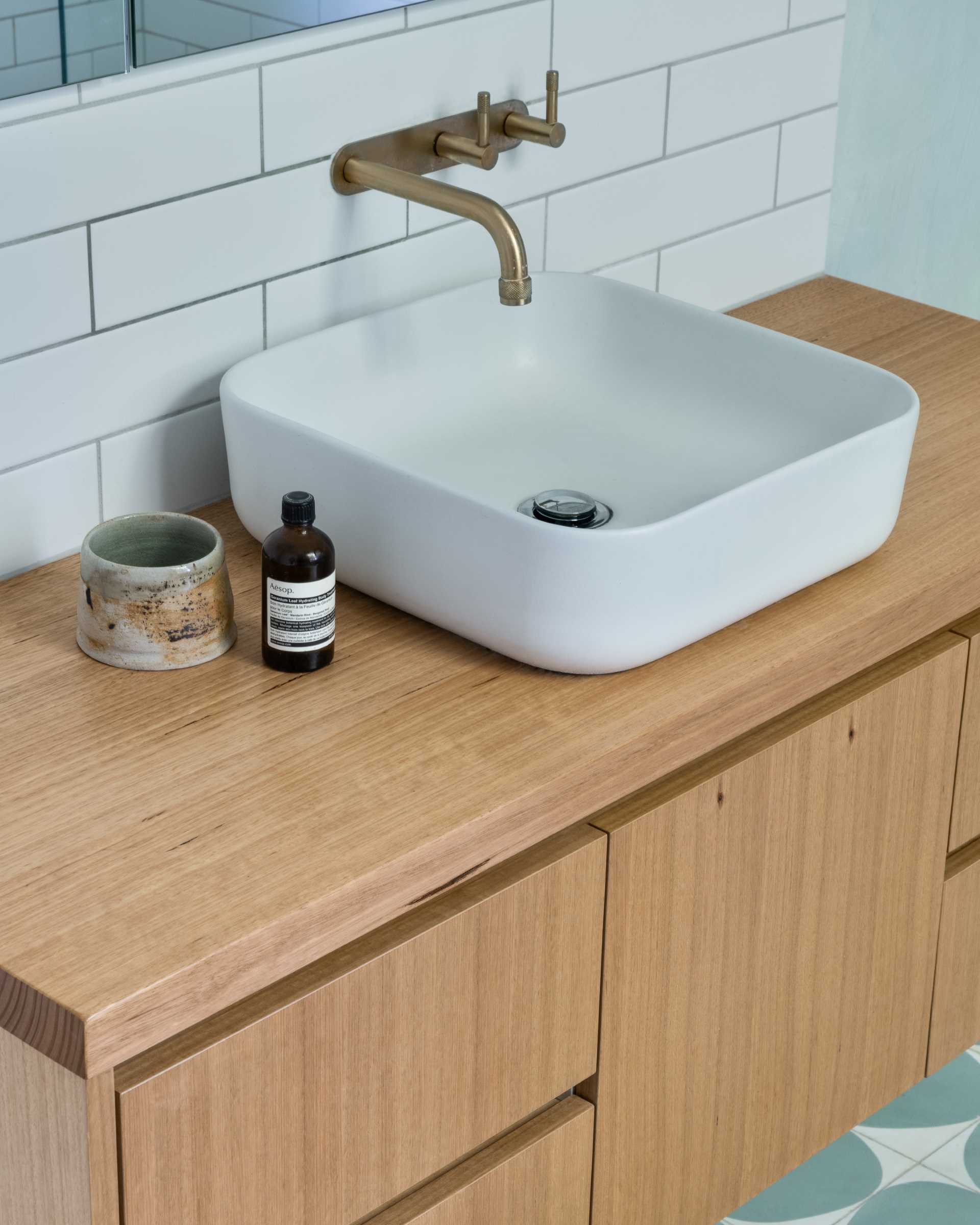 A contemporary bathroom with a wood vanity and white subway tiles.