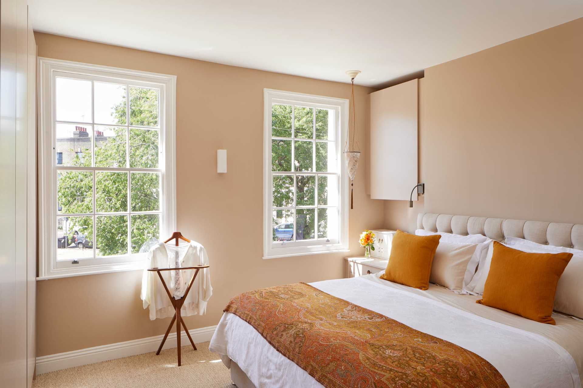 In this bedroom, a pair of 6-pane sash windows provide a view of the trees and street.