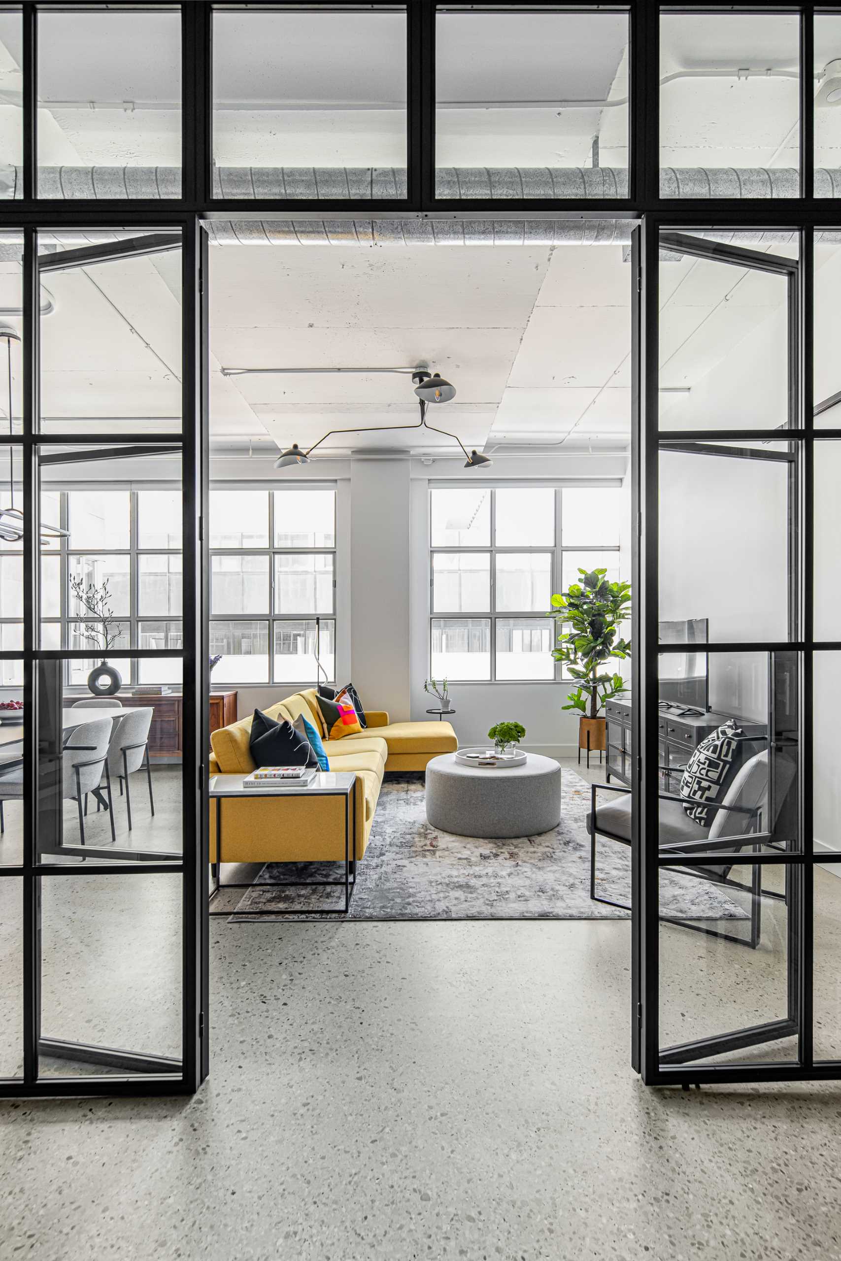 A modern glass enclosed library and home office looks out to the living room.