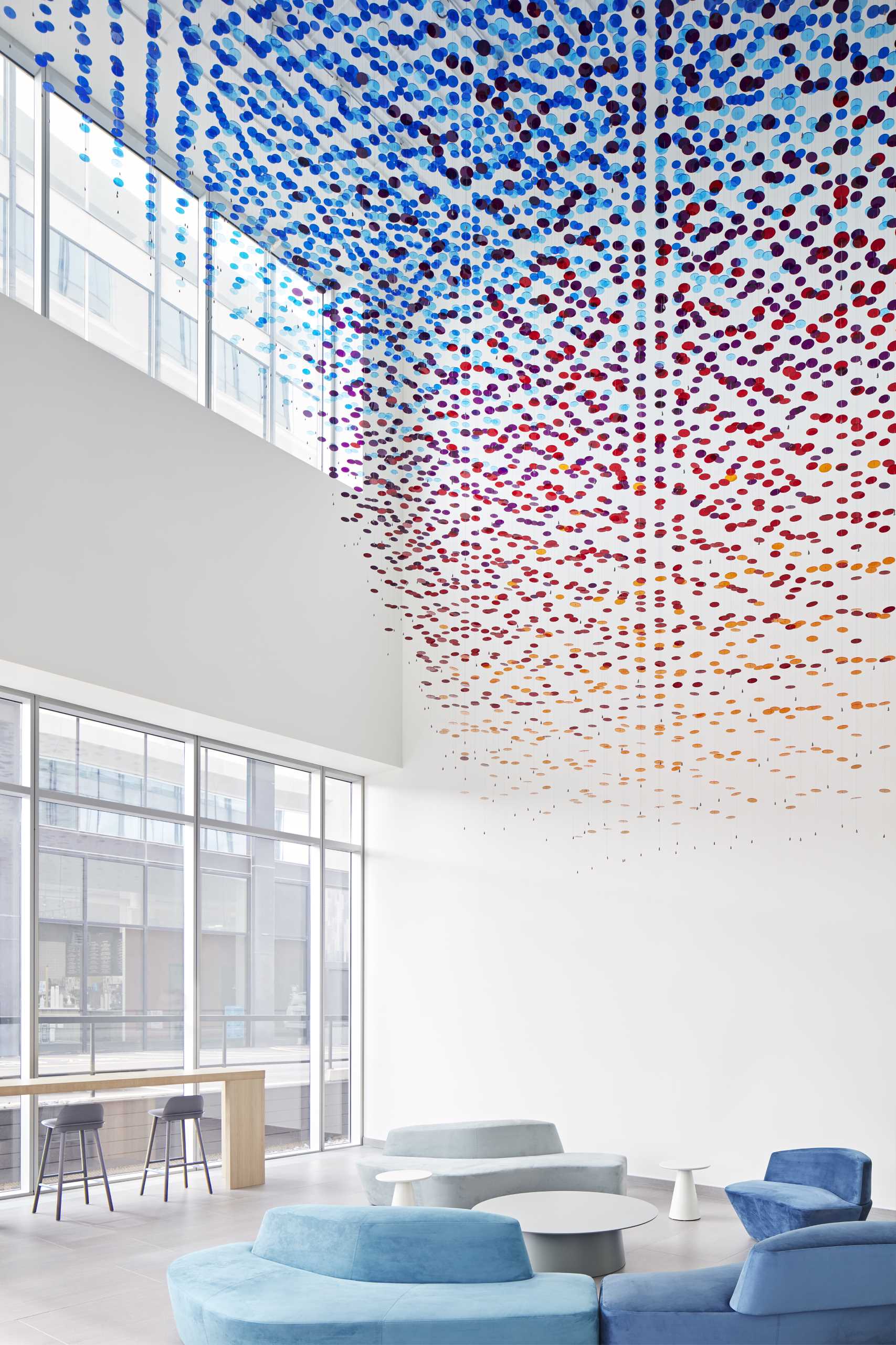 A custom-installation in a lobby atrium is made from 8,000 colorful discs suspended from 650 wire cables.