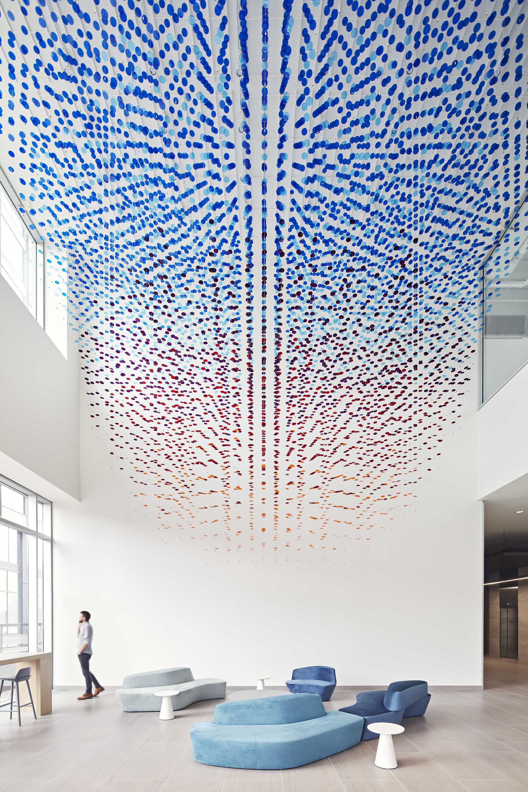 A custom art installation in a lobby atrium is made from 8,000 colorful discs suspended from 650 wire cables.