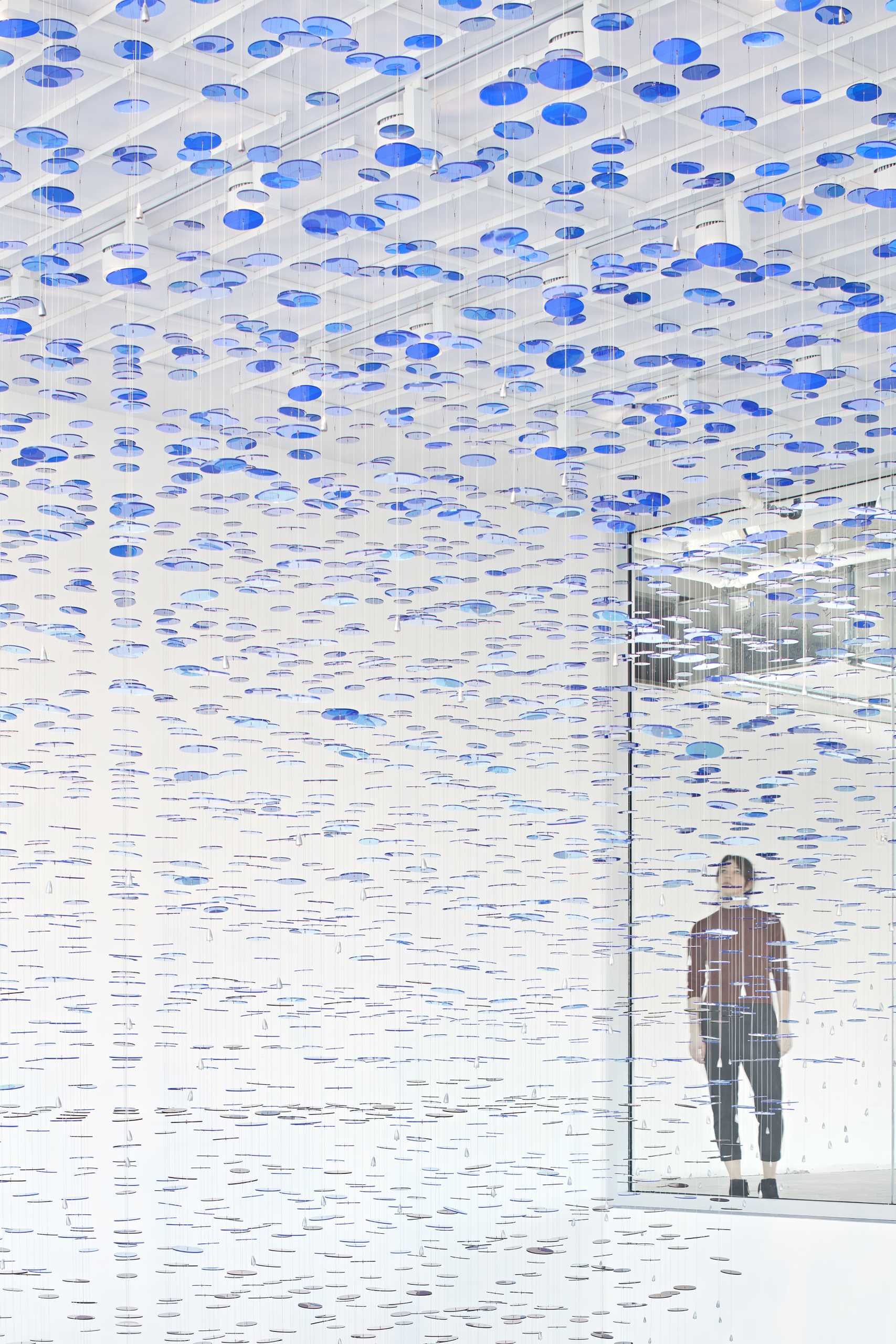 A custom art installation in a lobby atrium is made from 8,000 colorful discs suspended from 650 wire cables.