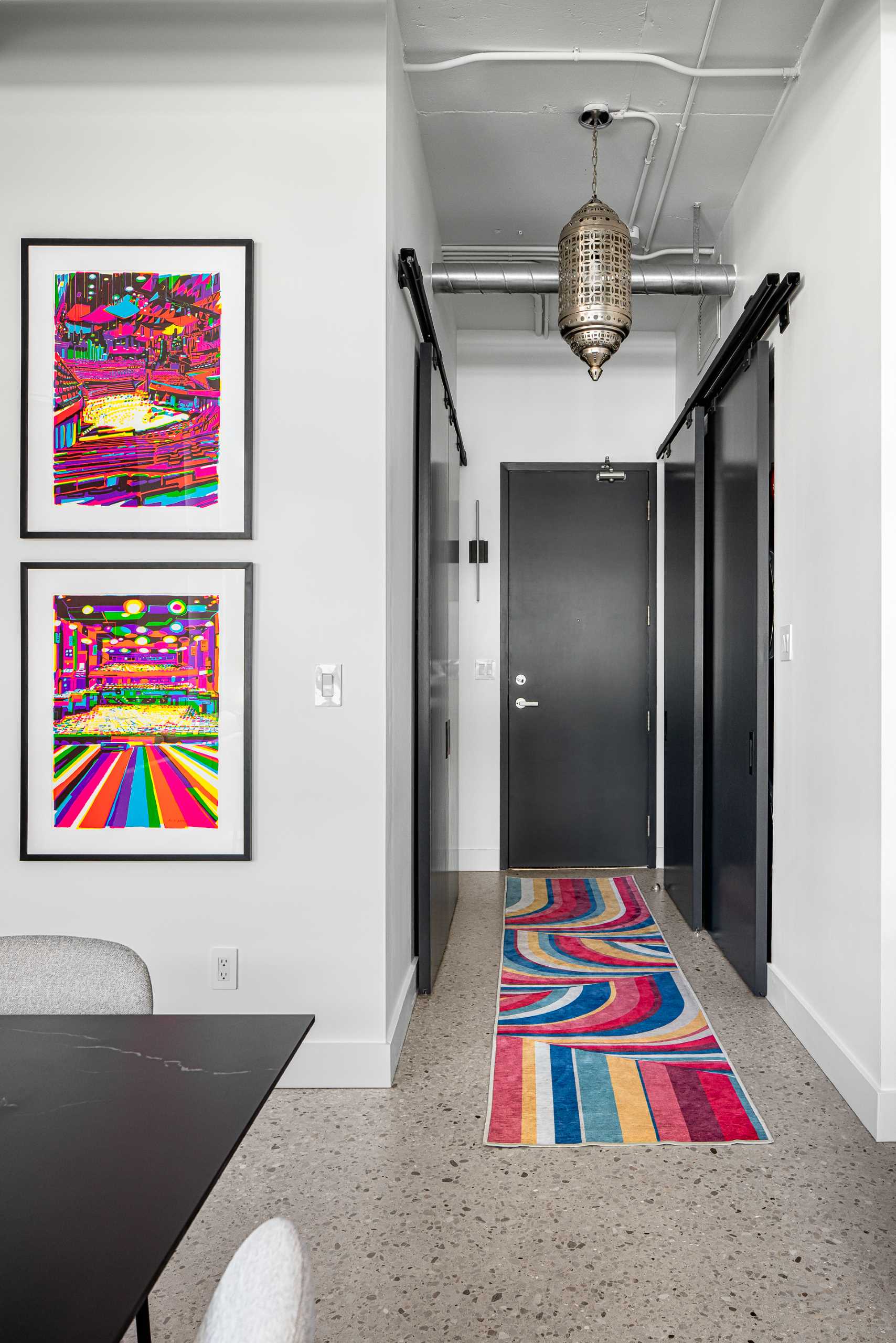 In this entryway, the designers worked with the existing sliding doors and rails in this unit, which were originally a dated yellowish natural wood color. Their solution was to prime and paint them black so they spoke with the other elements in the loft.