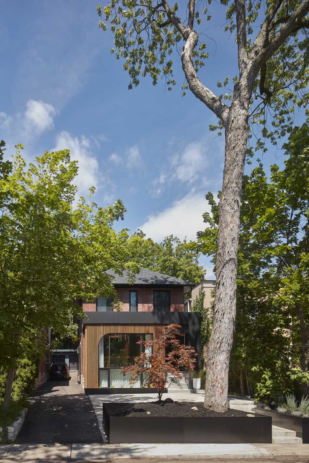 The exterior of the home, which is located in Toronto, Canada, has a large window that looks out onto the street and provides light to the ground level and the lower level.