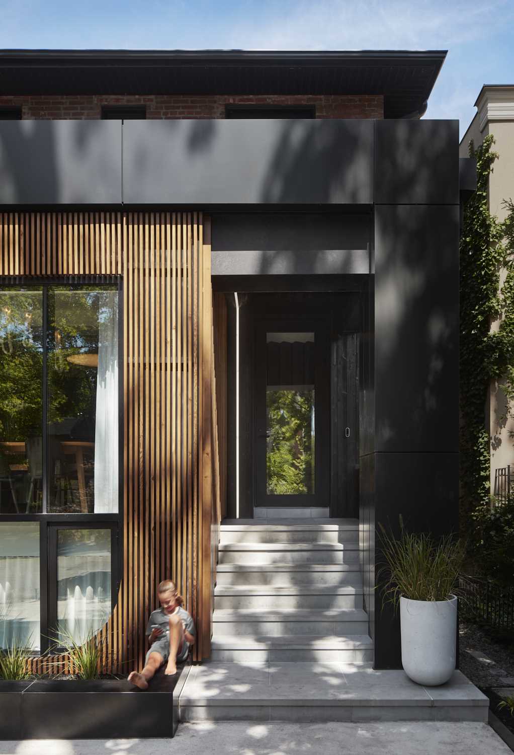 A partial wood slat facade softens the exterior of this modern house, while steps lead to the entryway and front door, which also includes LED lighting.