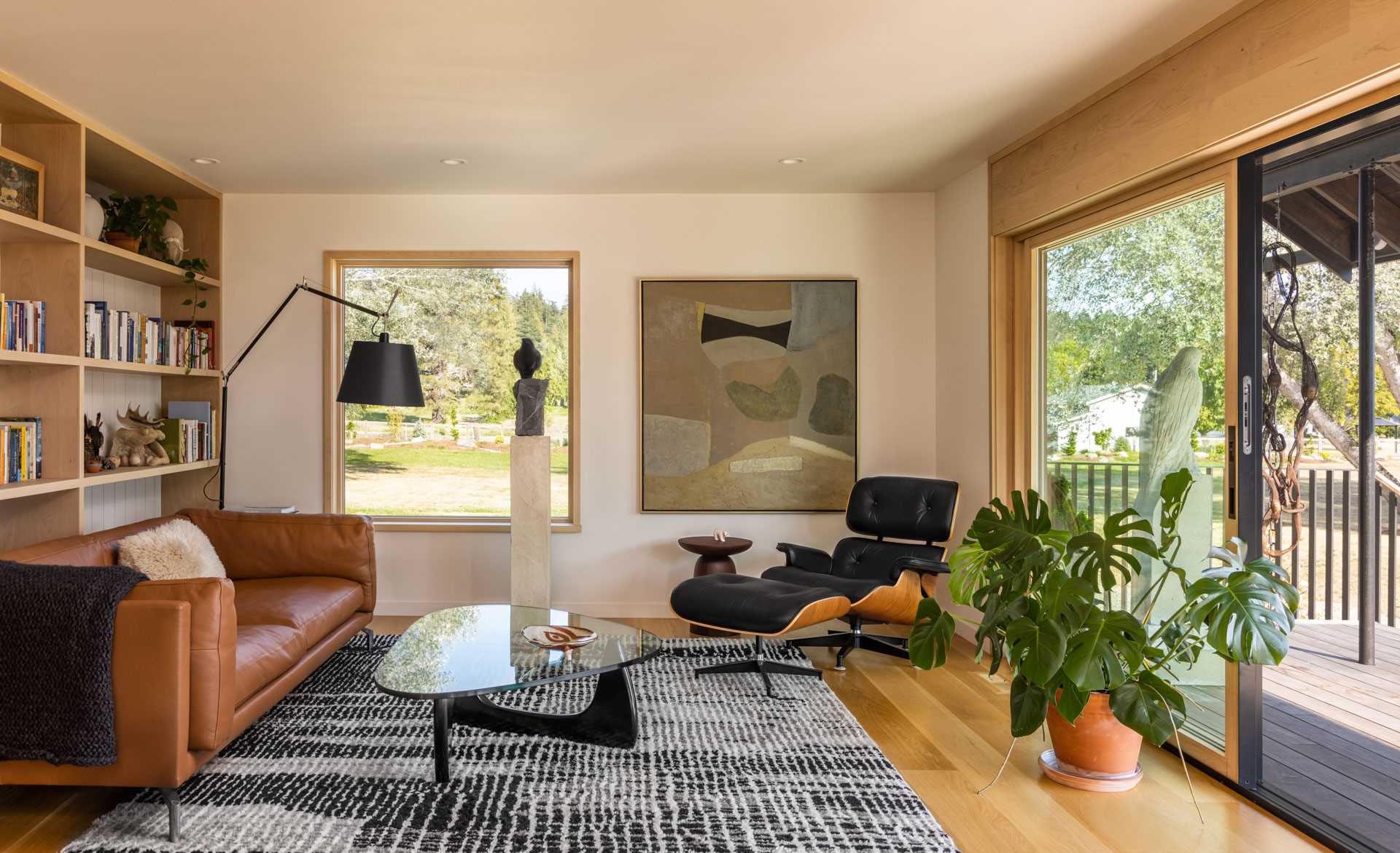 A remodeled living room with picture windows and wood shelving.