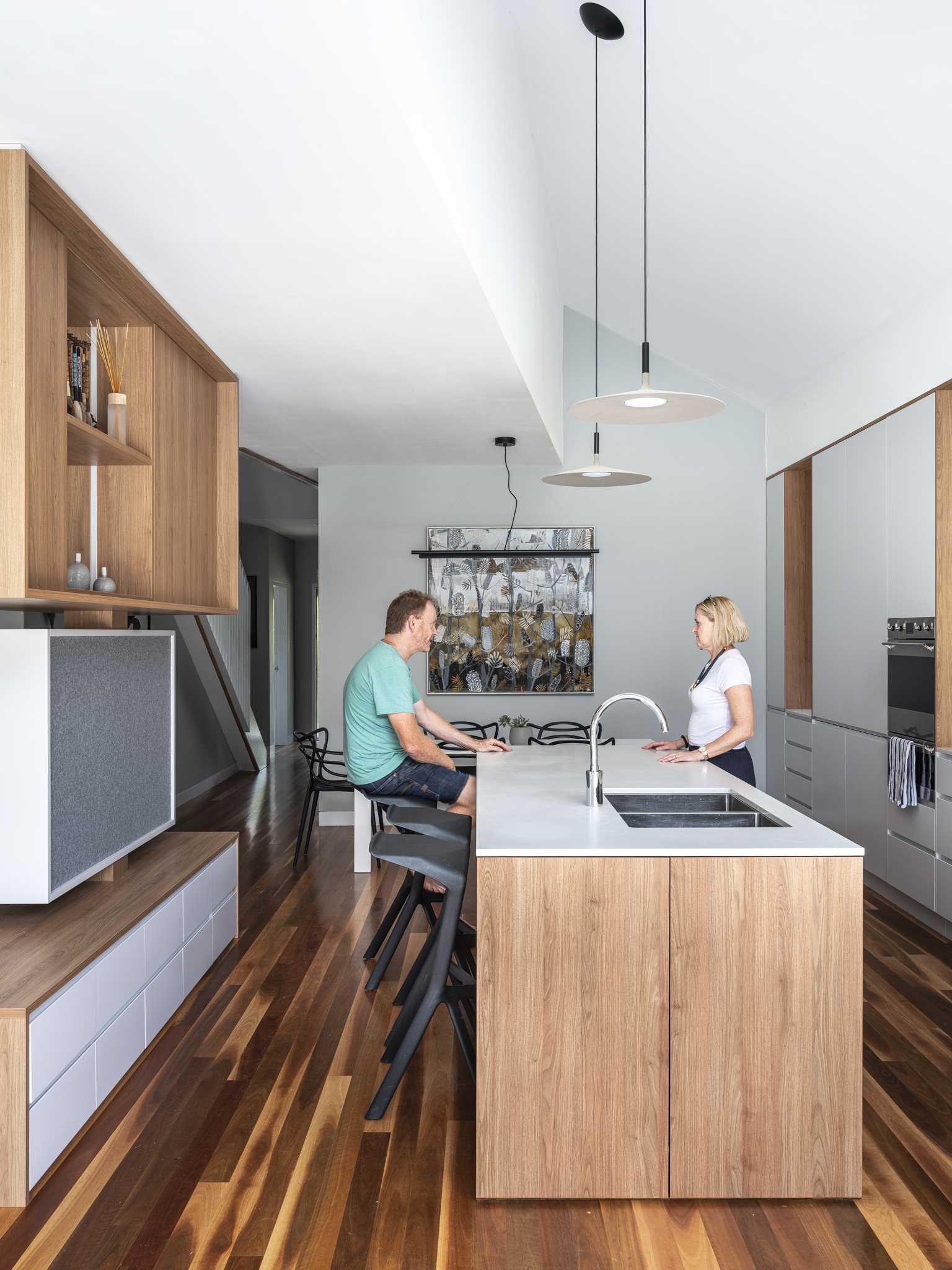 In this modern kitchen, wood and white cabinetry complement the wood floor and soften the concrete elements found outside.