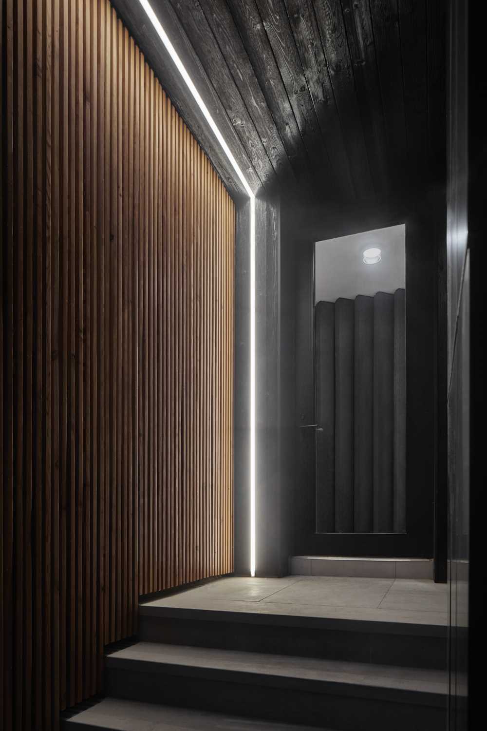 A partial wood slat facade softens the exterior of this modern house, while steps lead to the entryway and front door, which also includes LED lighting.