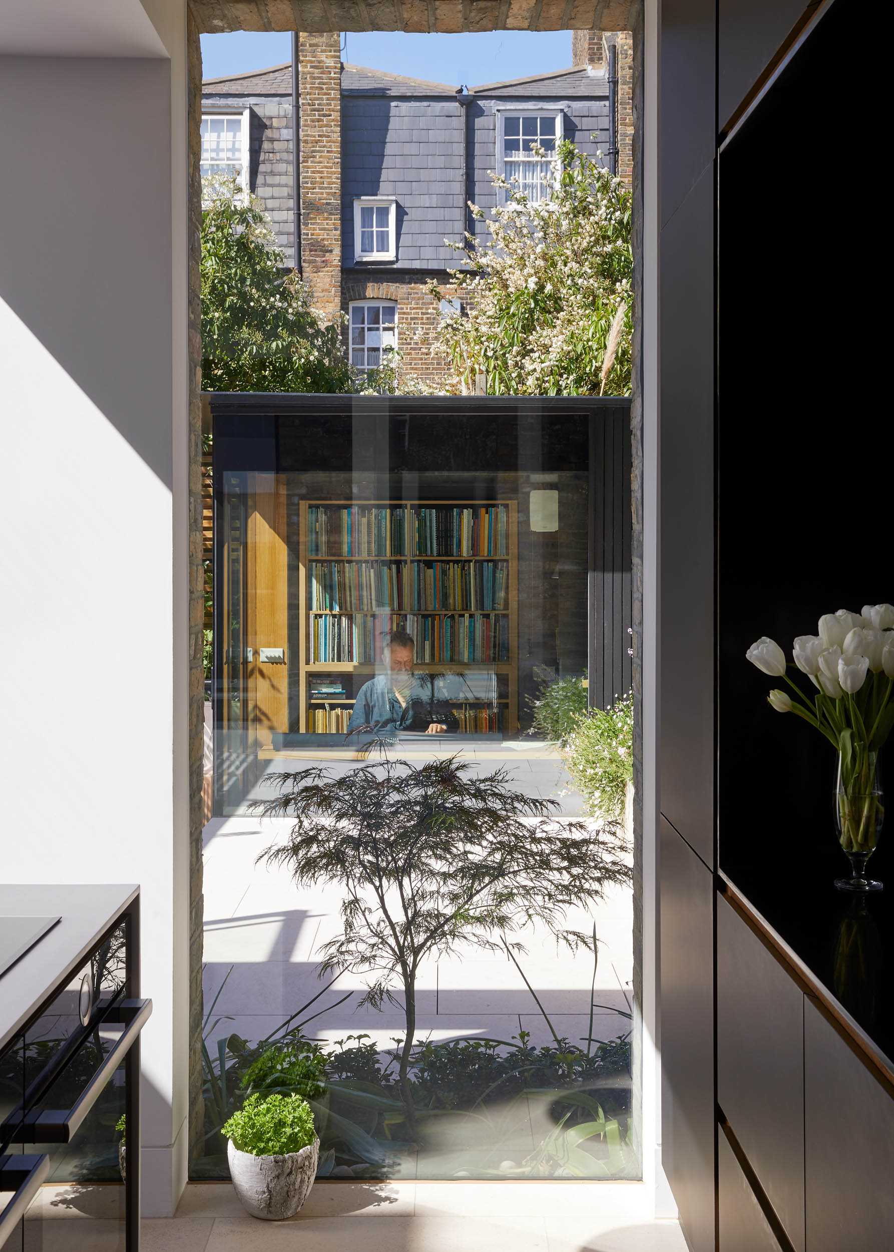 A kitchen with a floor-to-ceiling window that provides a view of the garden studio.