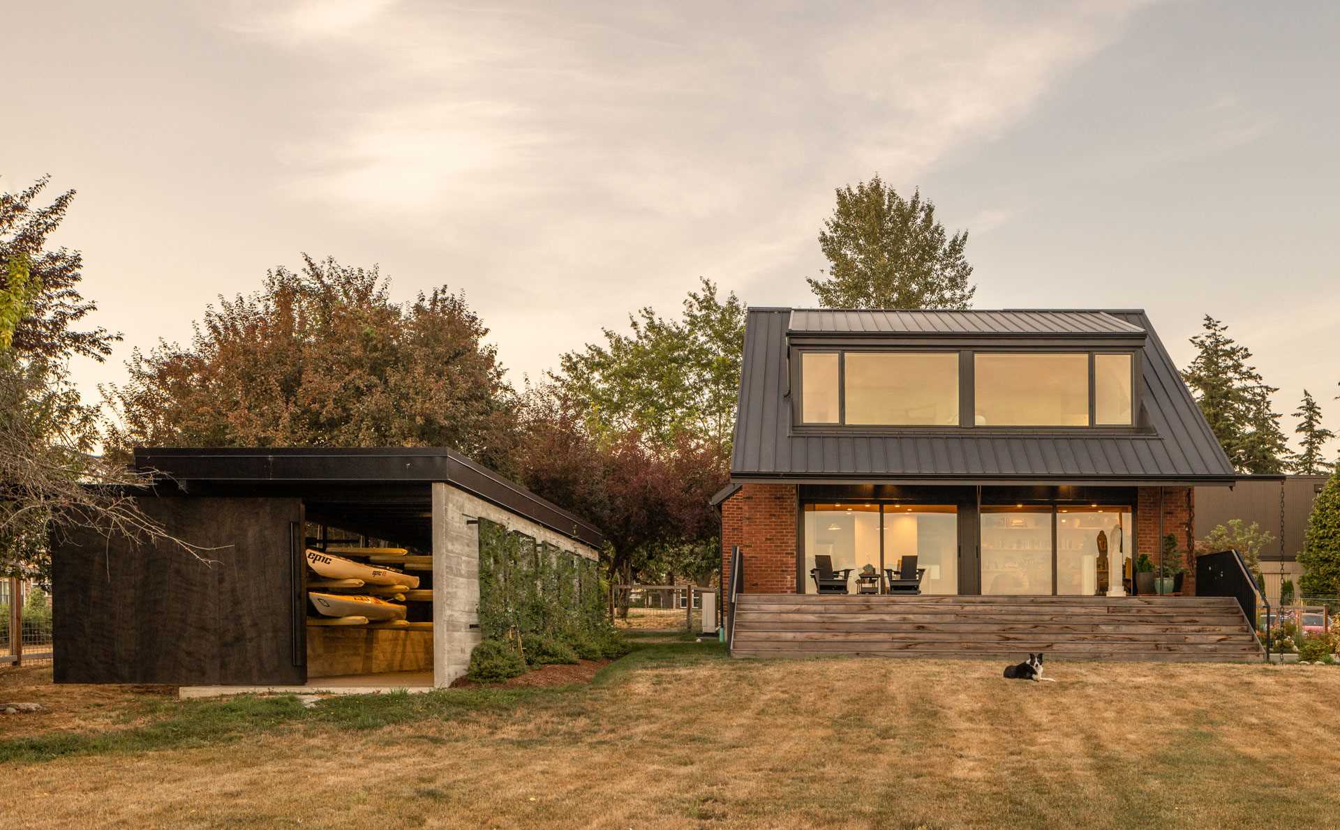 A modern brick house with a boathouse that includes storage and a large sliding door.