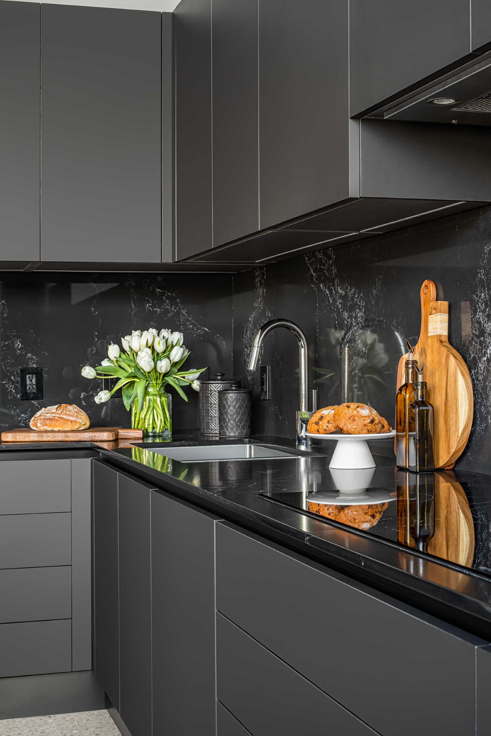 A modern kitchen with a white stone island with subtle veins and minimalist hardware-free black cabinets.