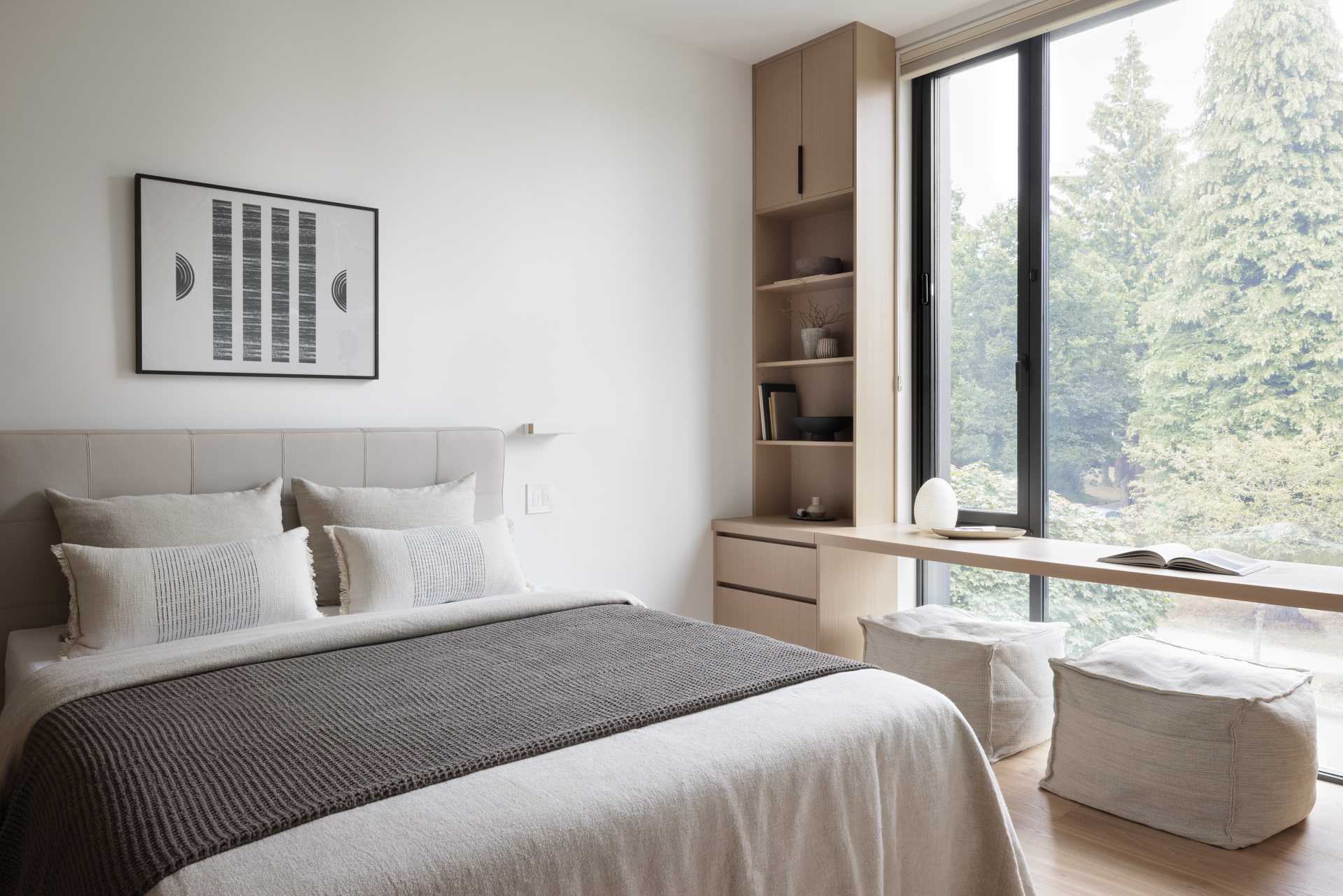 A modern bedroom with custom joinery and a desk in front of the window.
