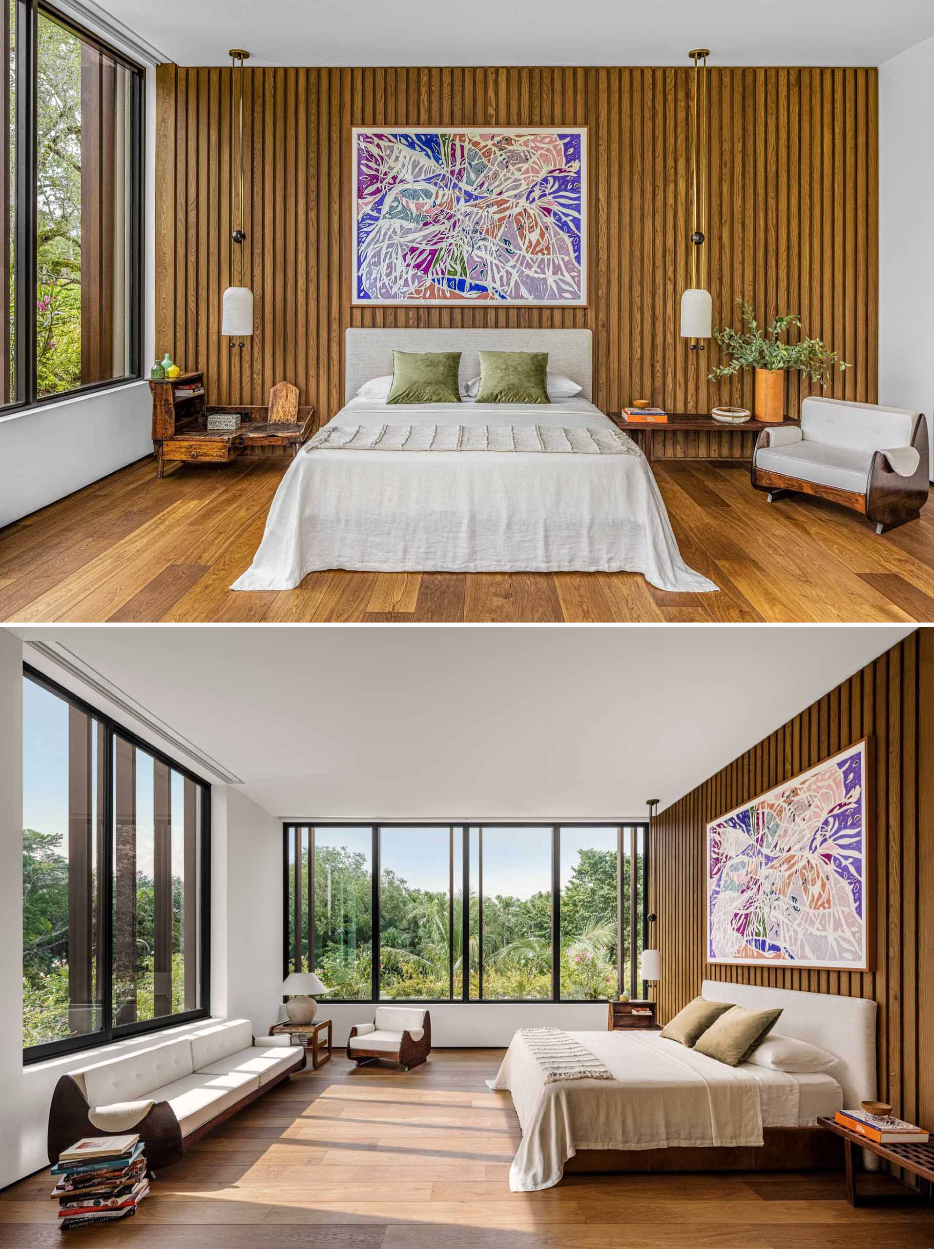In this primary bedroom, wood lines the wall, while the light fixtures are by Apparatus Studio and the painting is by Marcia de Moraes. George Nelson benches serve as bedside tables.