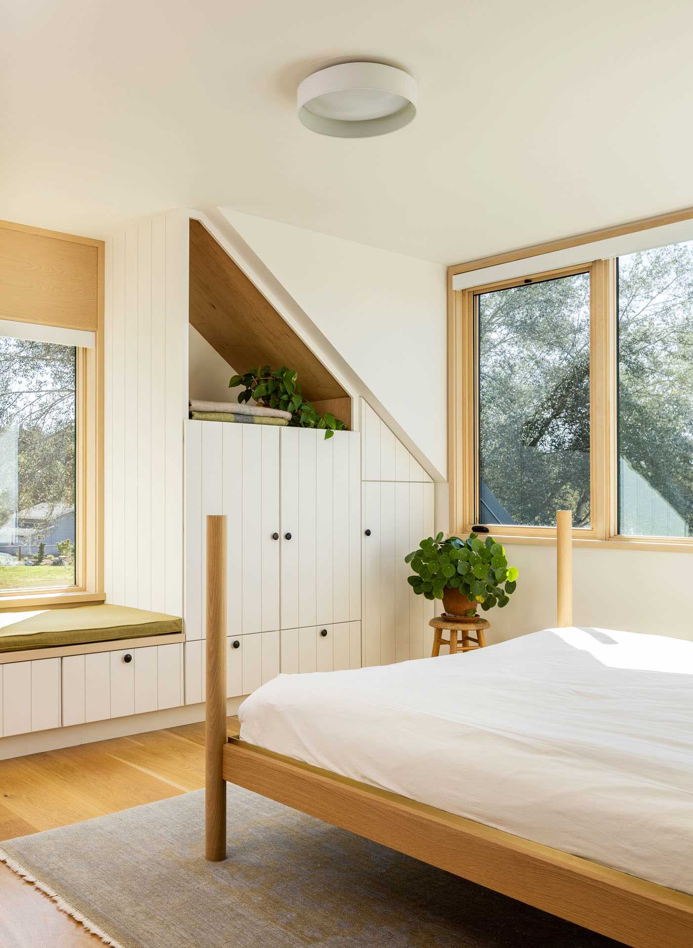 A contemporary farmhouse-inspired bedroom with a picture window, built-in storage, and a window beach.