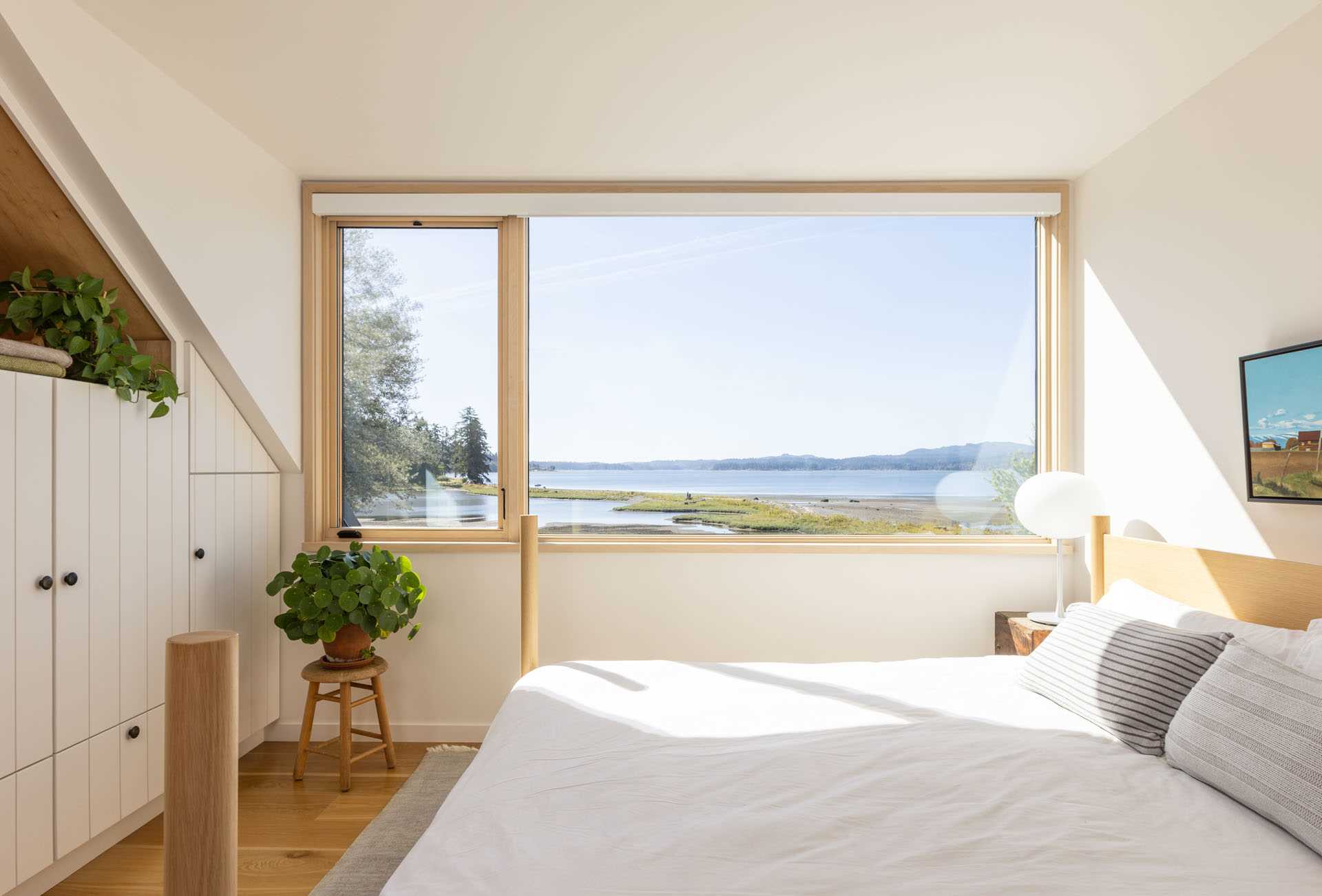 A contemporary farmhouse-inspired bedroom with a picture window, built-in storage, and a window beach.