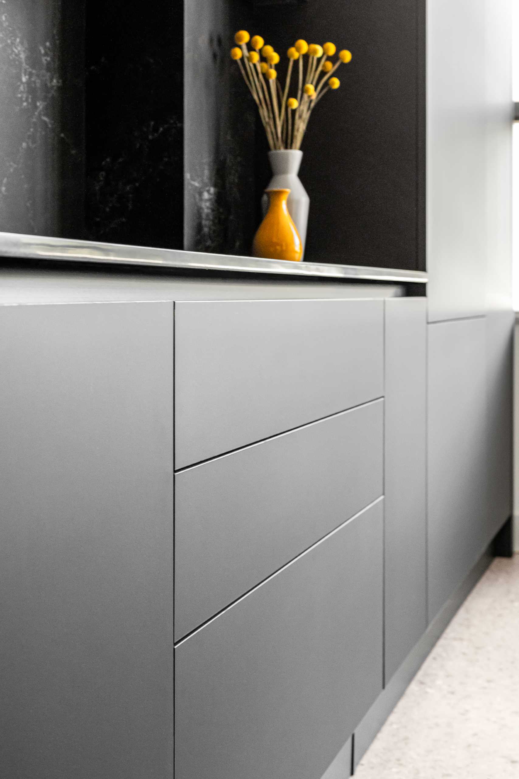 A modern kitchen with a white stone island with subtle veins and minimalist hardware-free black cabinets.