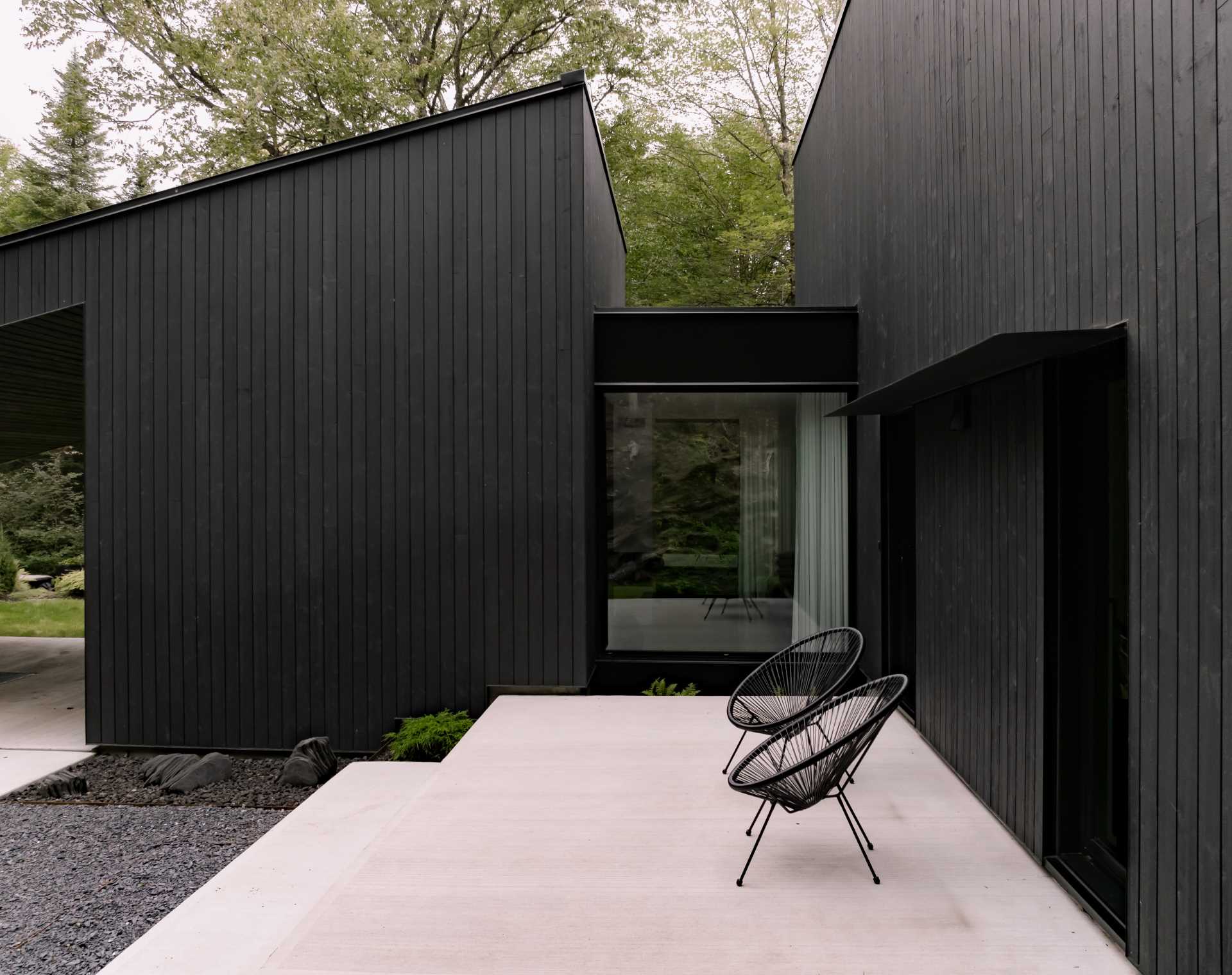 A modern black home with a wood porch.