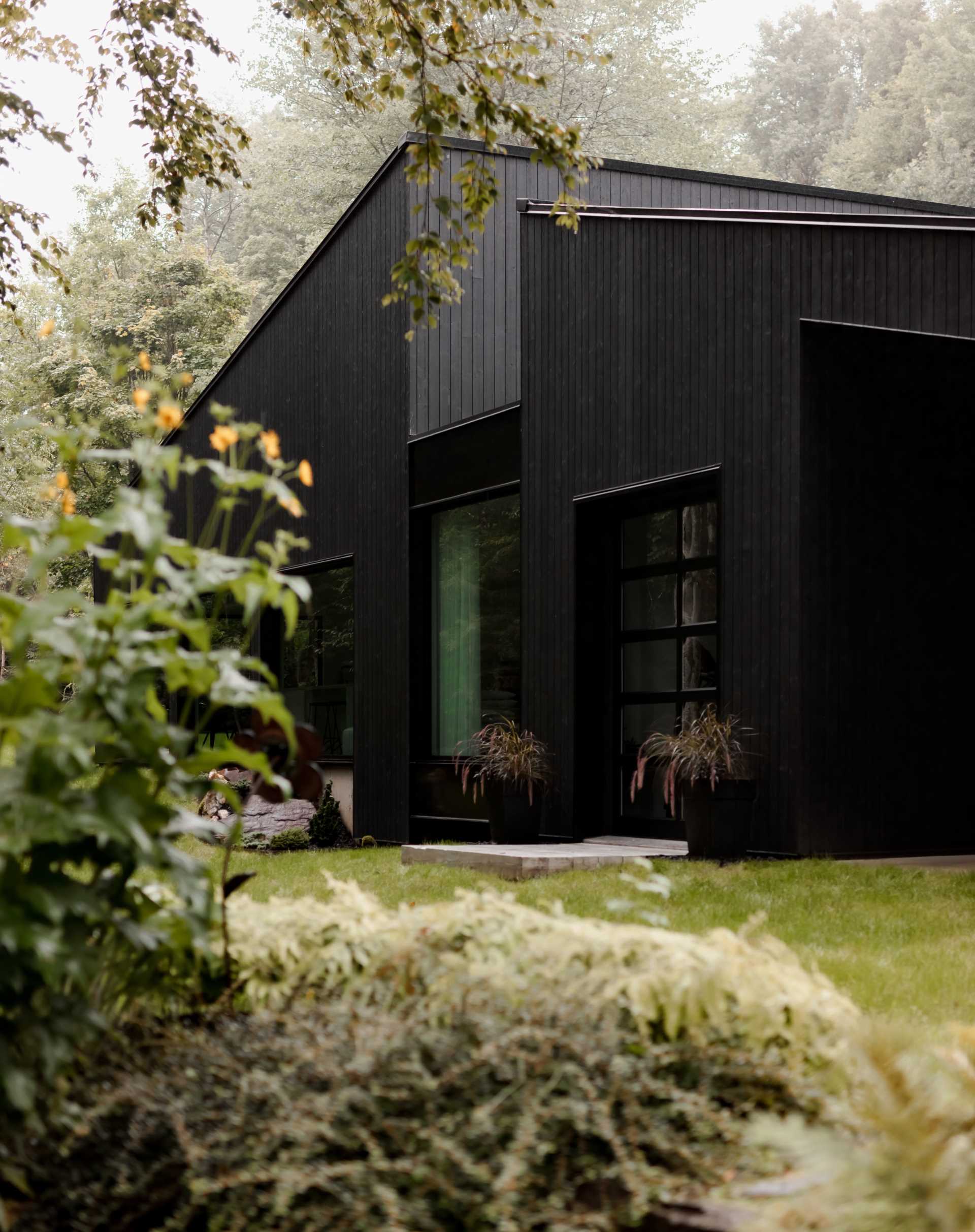 This modern home has a black wood exterior, with black window frames providing consistency to the design.