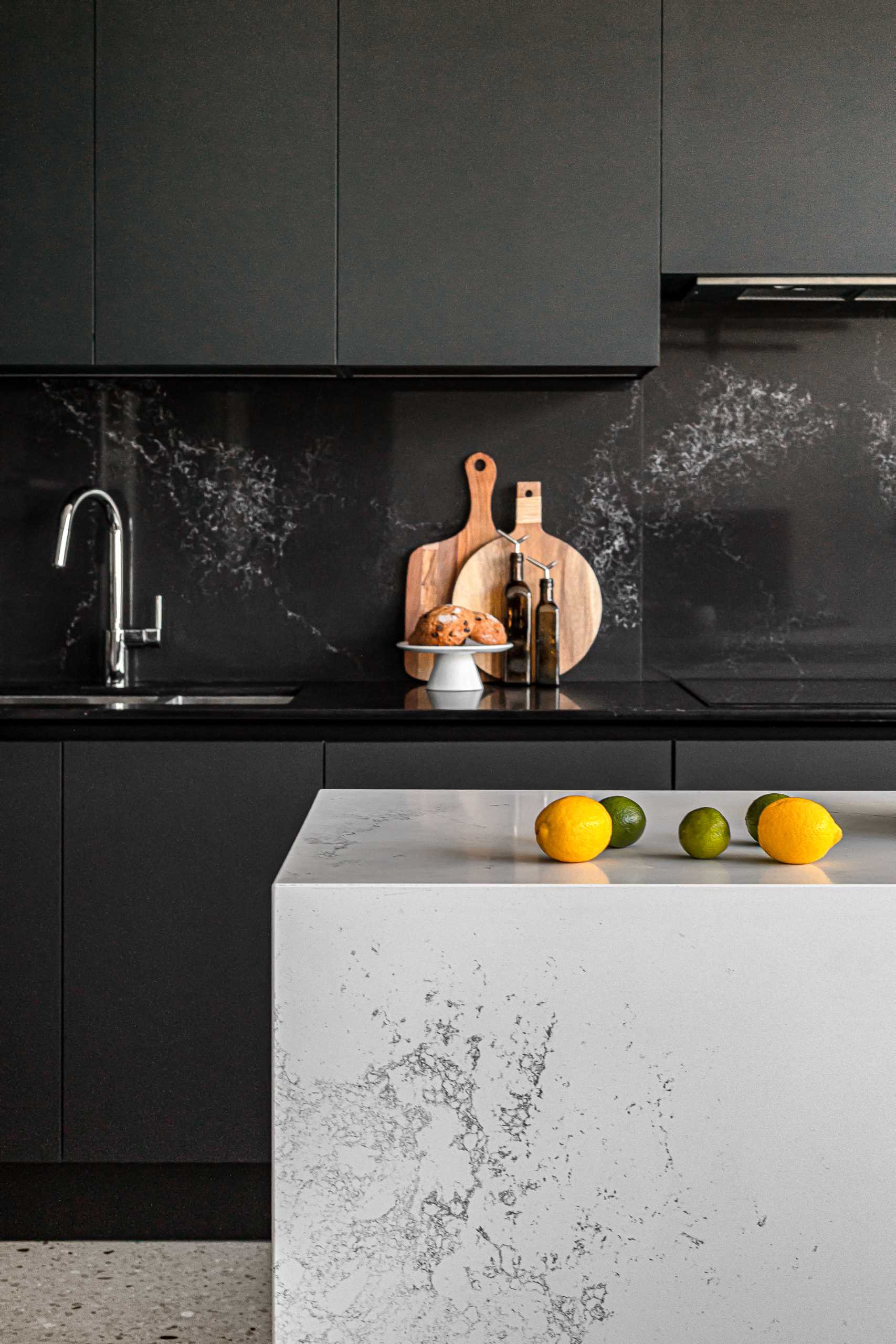 A modern kitchen with a white stone island with subtle veins and minimalist black cabinets.