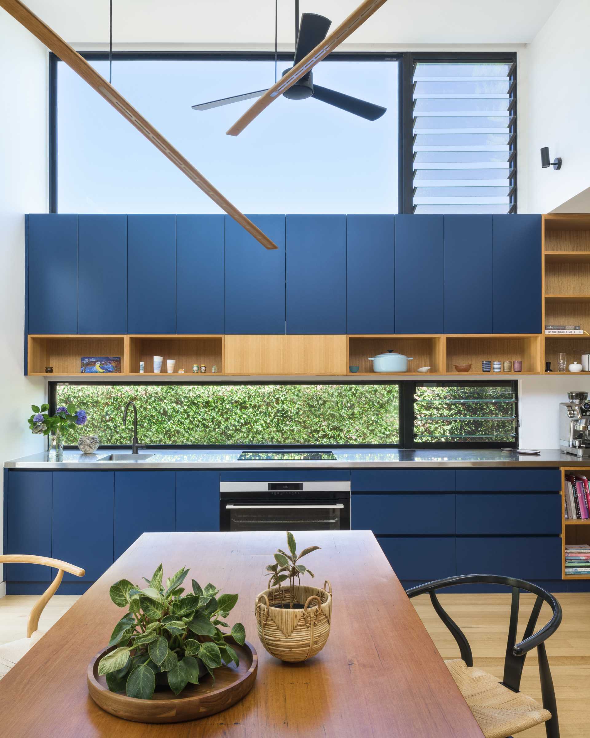 Instead of having a large island in this modern blue kitchen, the homeowners wanted a 'country kitchen' with a large table around which people gather to prepare food.