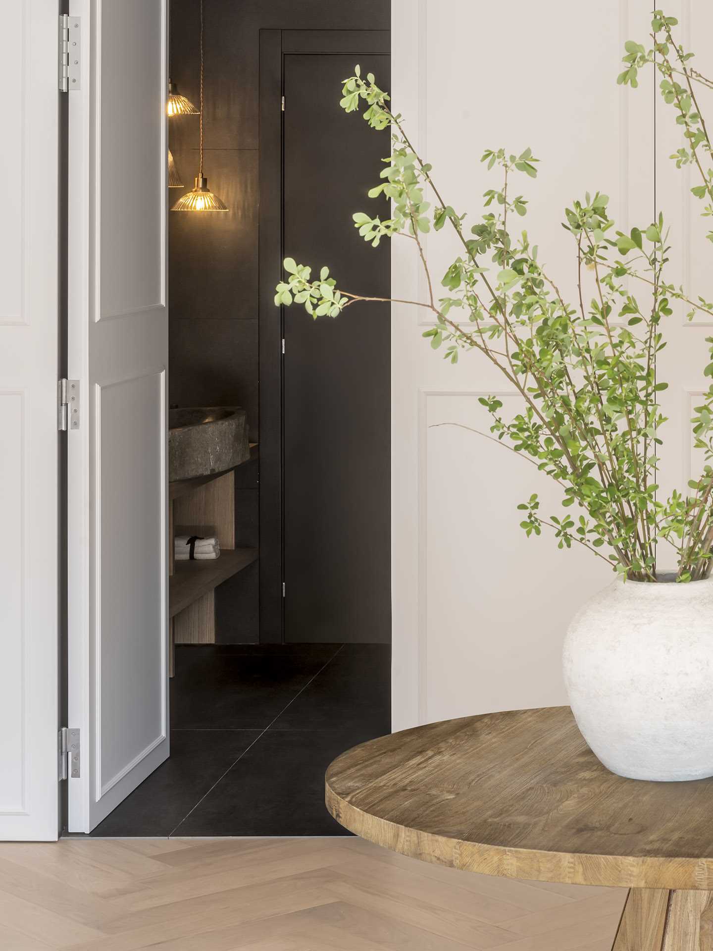 This modern powder room, with its dark walls and floors, is a strong contrast to the rest of the light interior.