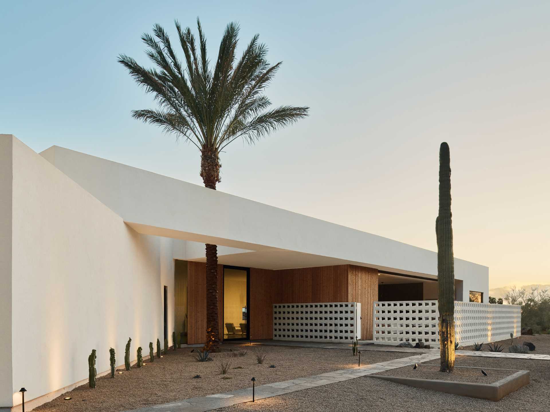 The entry of this house is highlighted by a singular date palm tree growing through a triangular aperture to the sky.