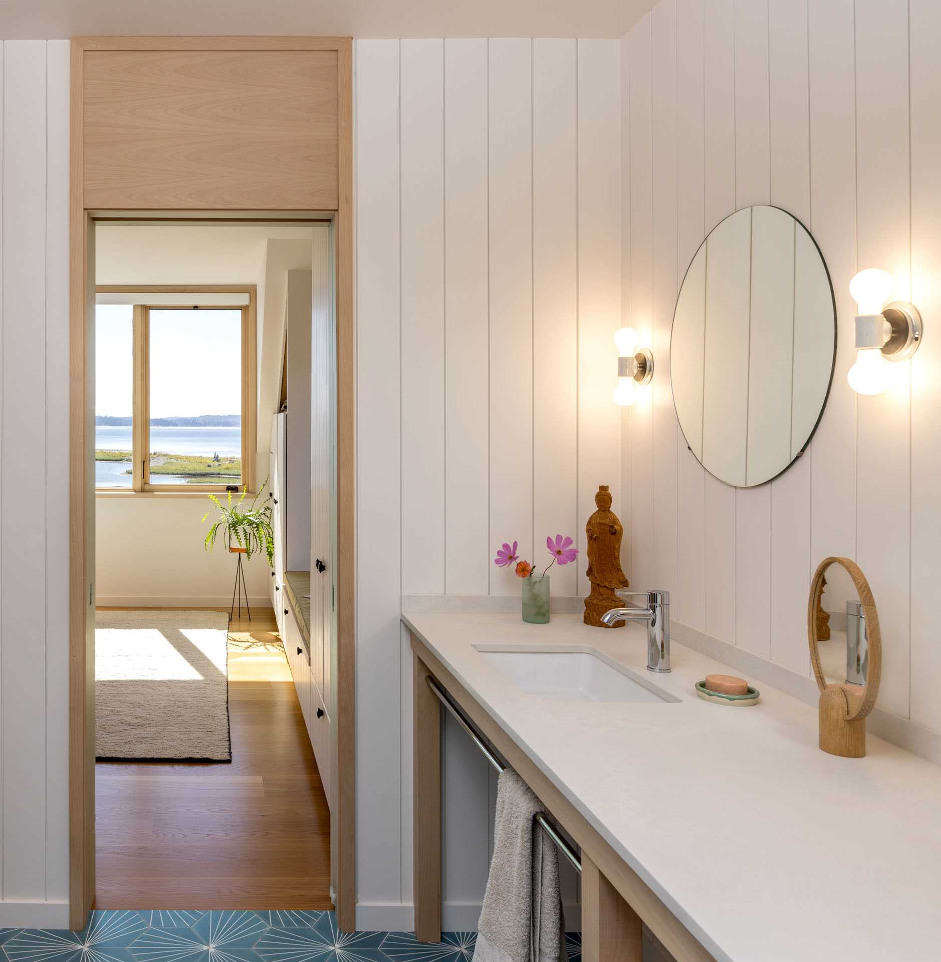 A contemporary farmhouse bathroom with a wood vanity and round mirror.