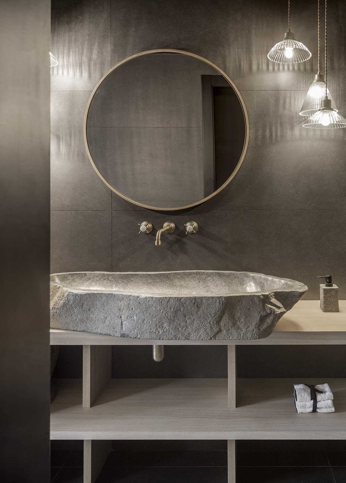 This modern powder room, with its dark walls and floors, is a strong contrast to the rest of the light interior.
