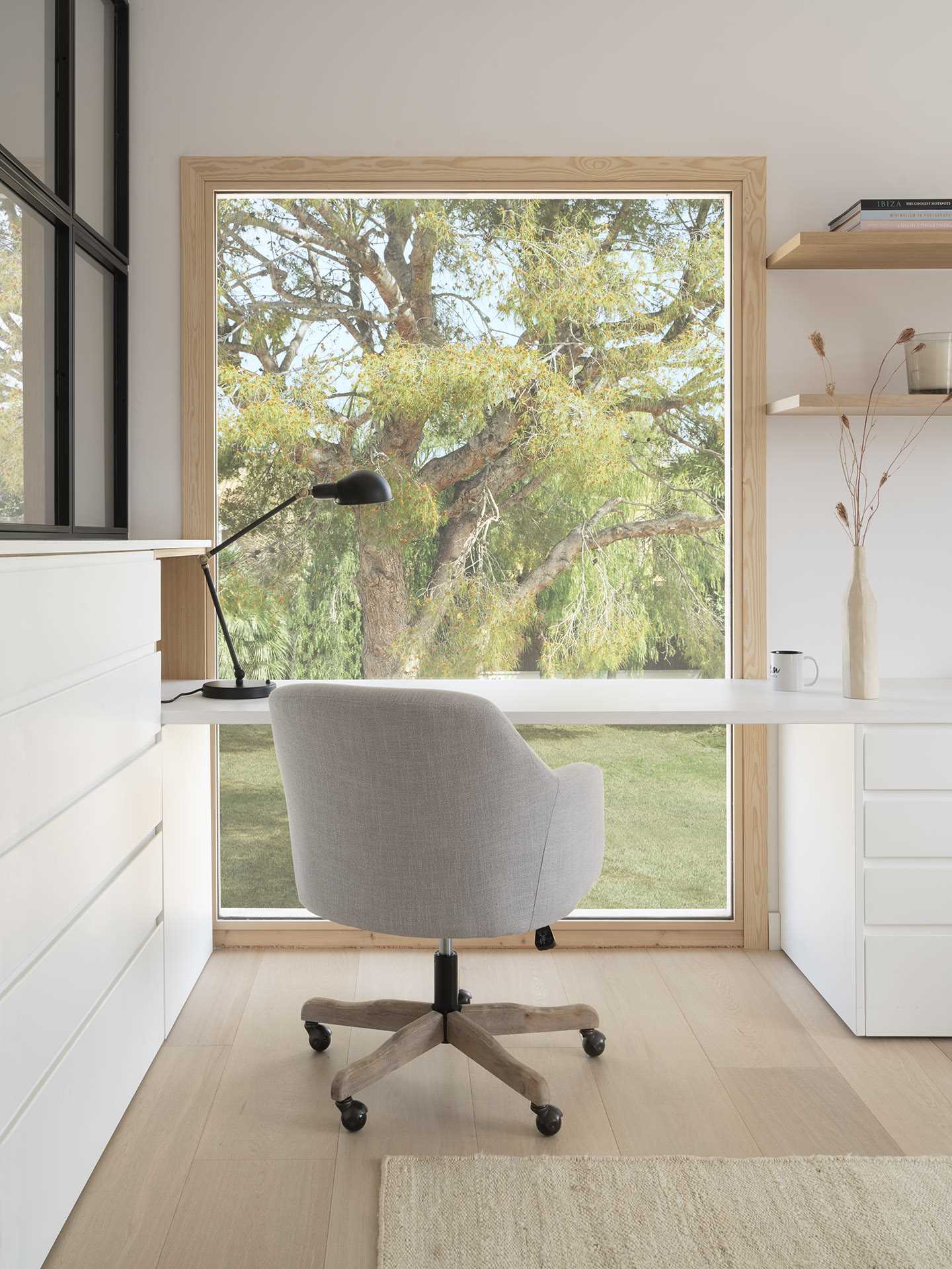 A modern home office with a desk in front of a large picture window.