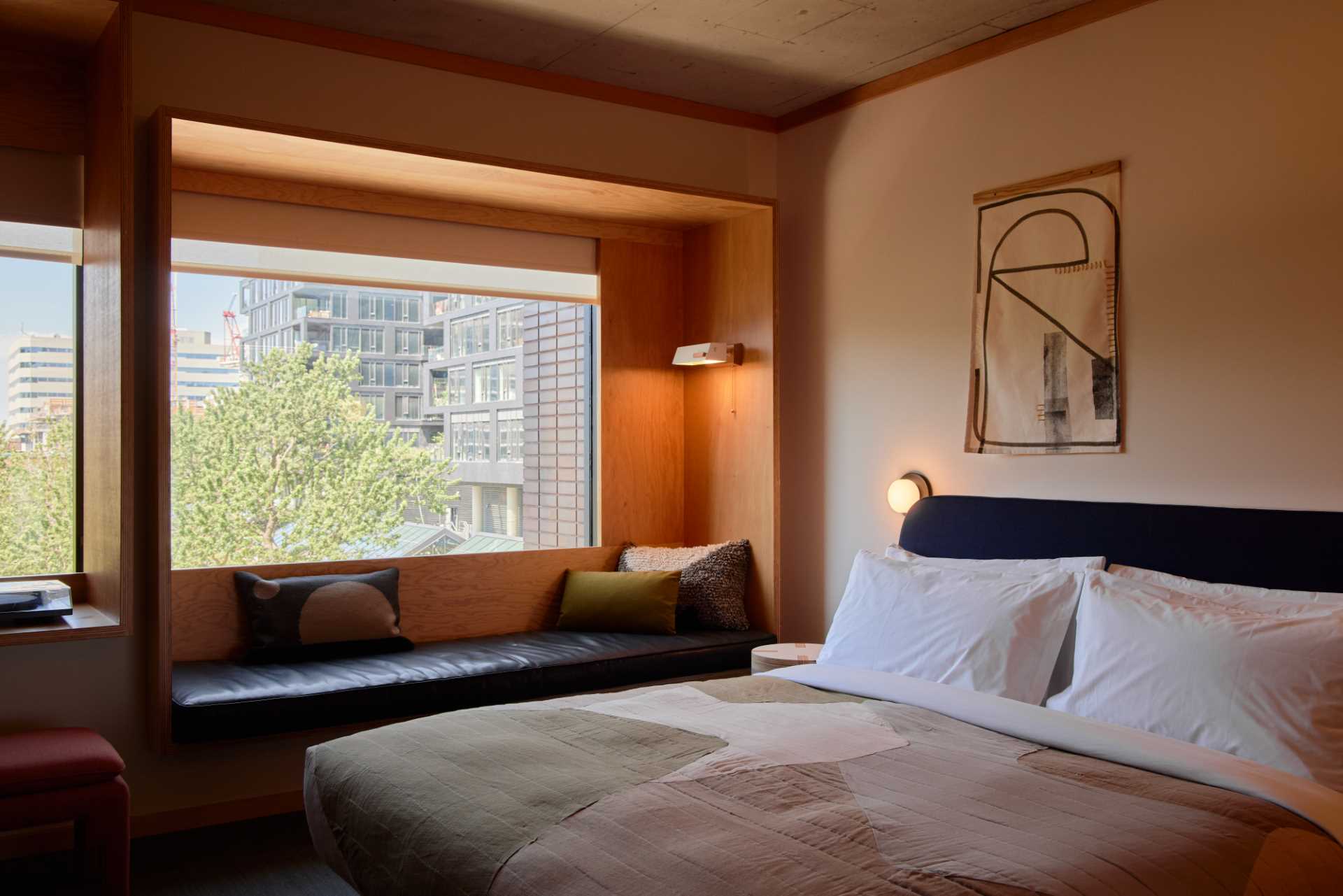 This modern hotel room includes a built-in window bench provides a place to enjoy the tree and city views.