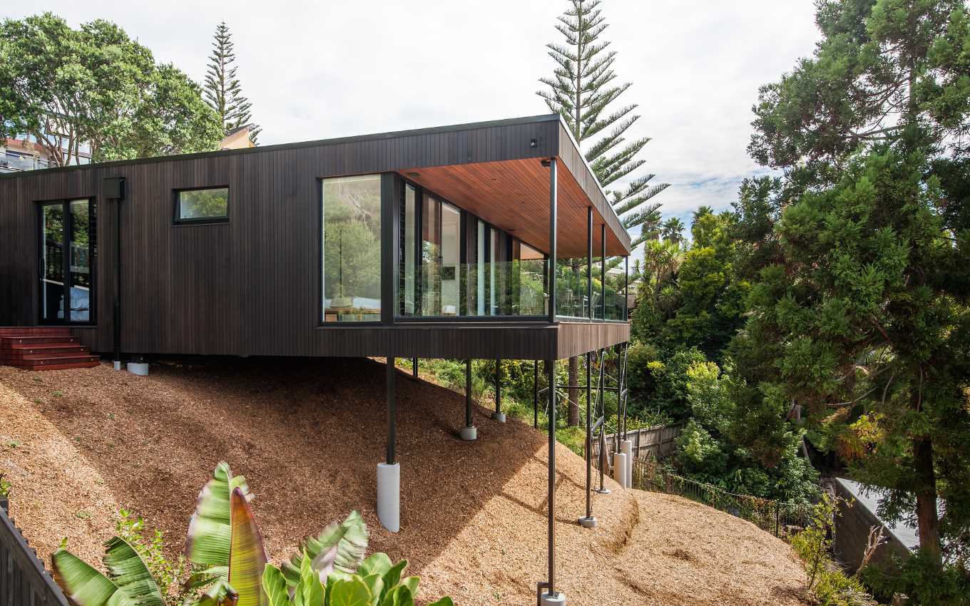 A modern home that's located on a sloped site, that overtime, will fill with plants.