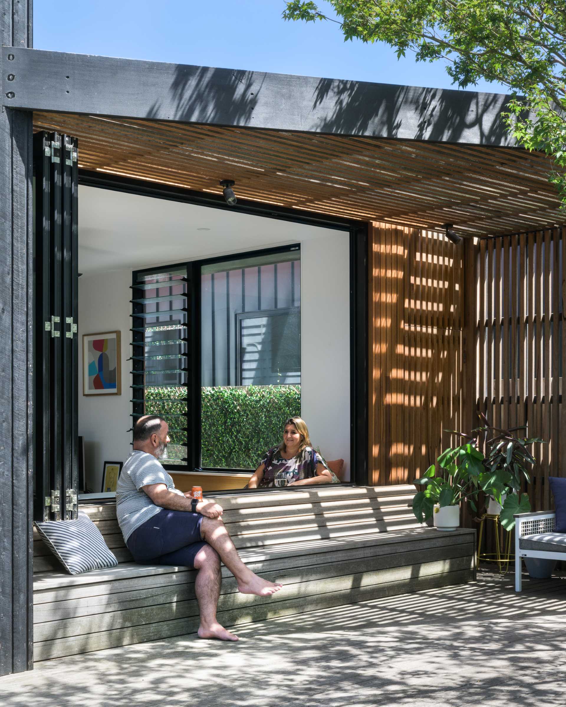 This modern deck has been designed with a shaded area that's home to built-in seating and a couch.