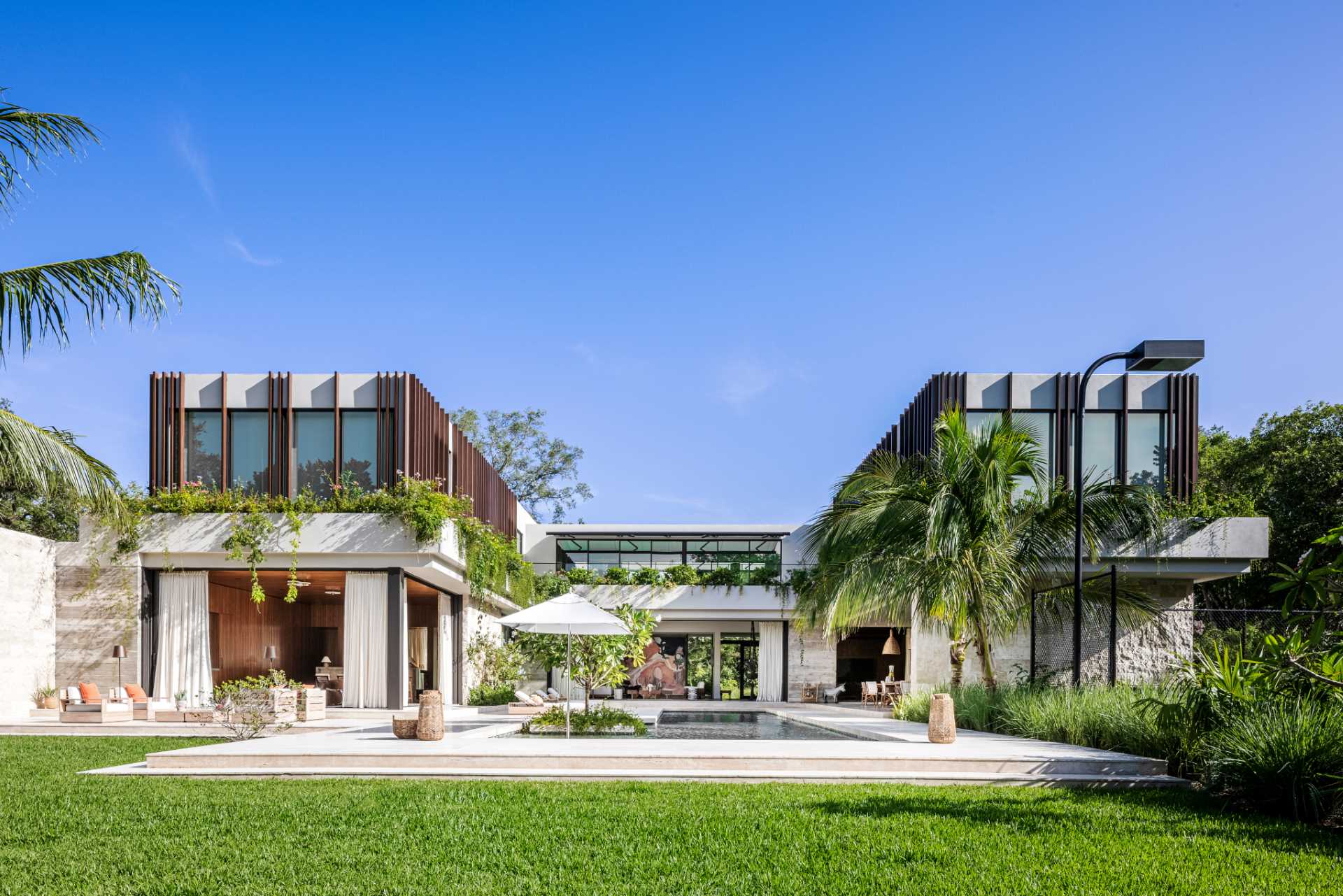 The exterior facade of this modern home features rough-cut Jerusalem tile and exposed board-formed concrete, as well the vertical Ipe wood fins and planters that wrap around the second storey.