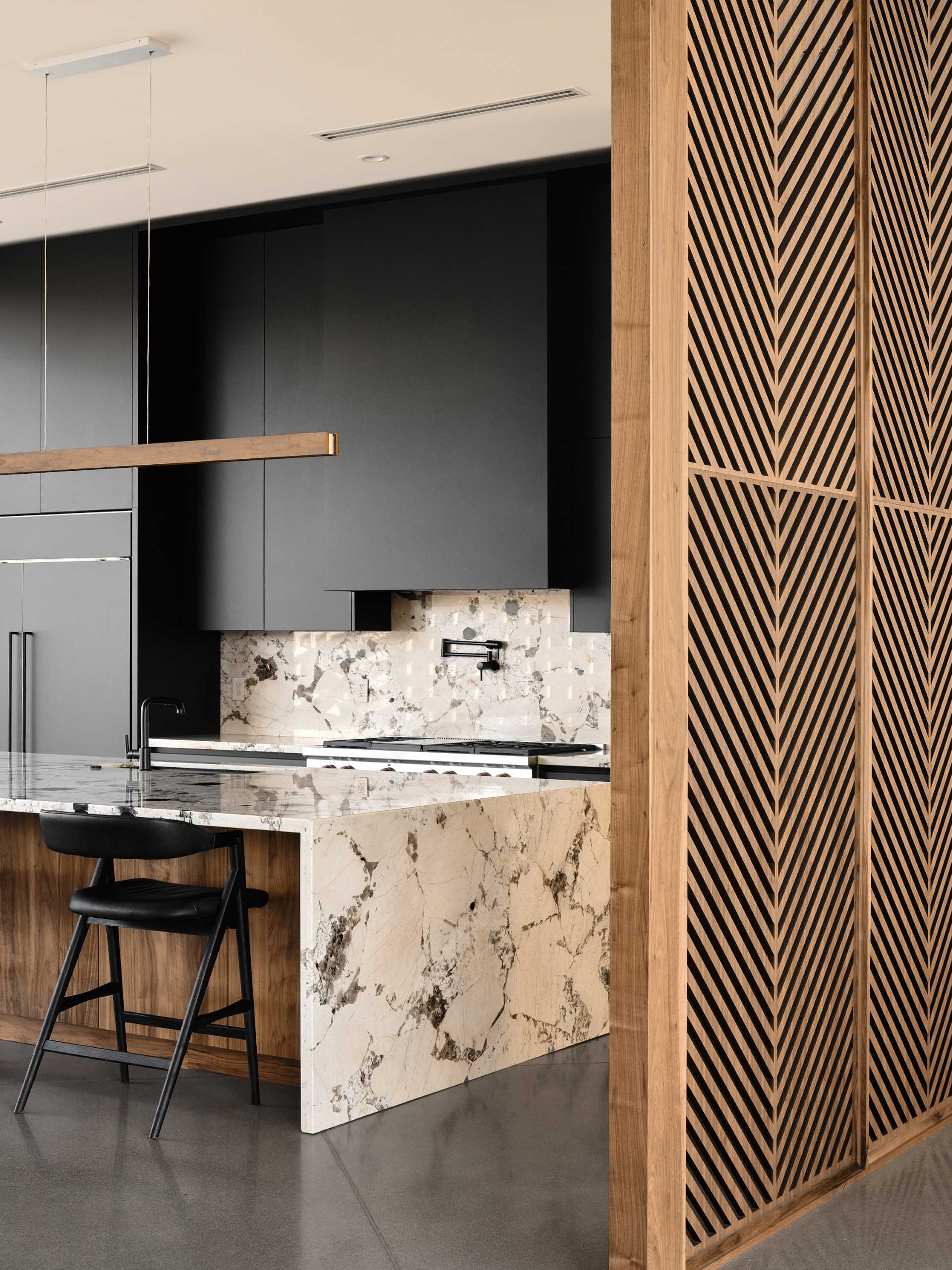 A modern kitchen with a wood partition screen with wood panels inspired by palm fronds.