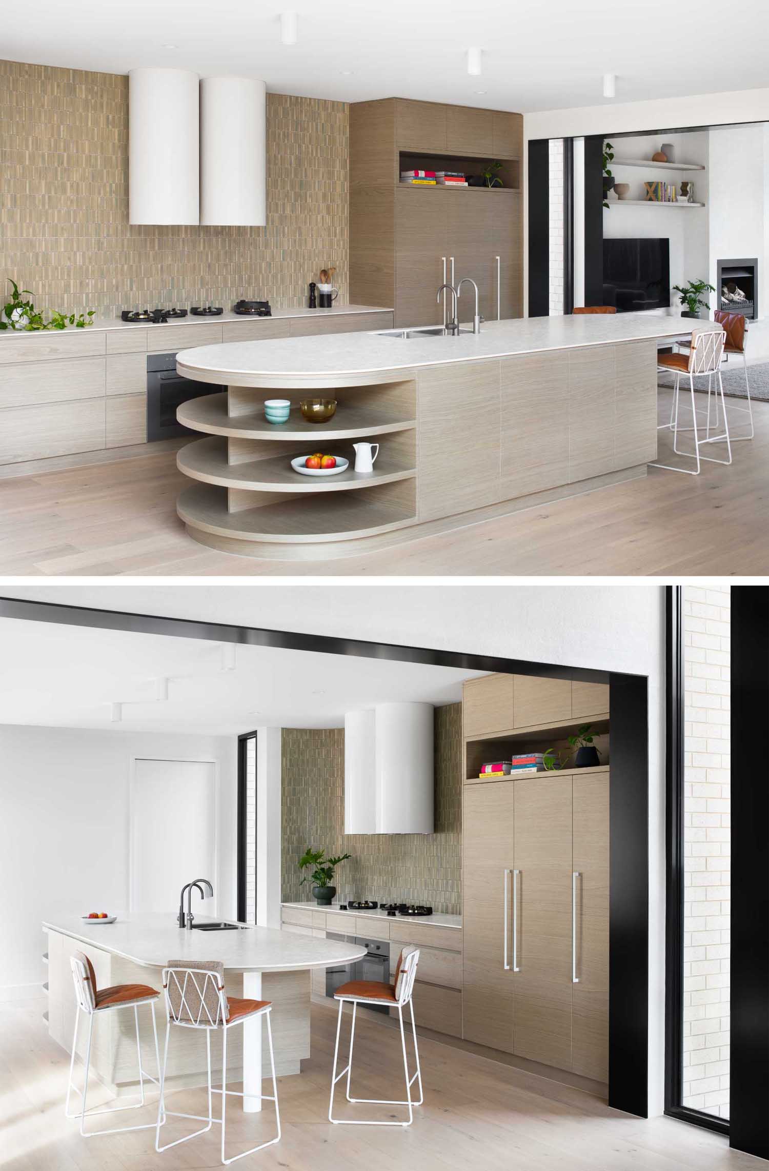 This modern kitchen features a tiled wall, wood cabinets, and an island with curved ends. One end is dedicated to seating, while the other has open shelving.