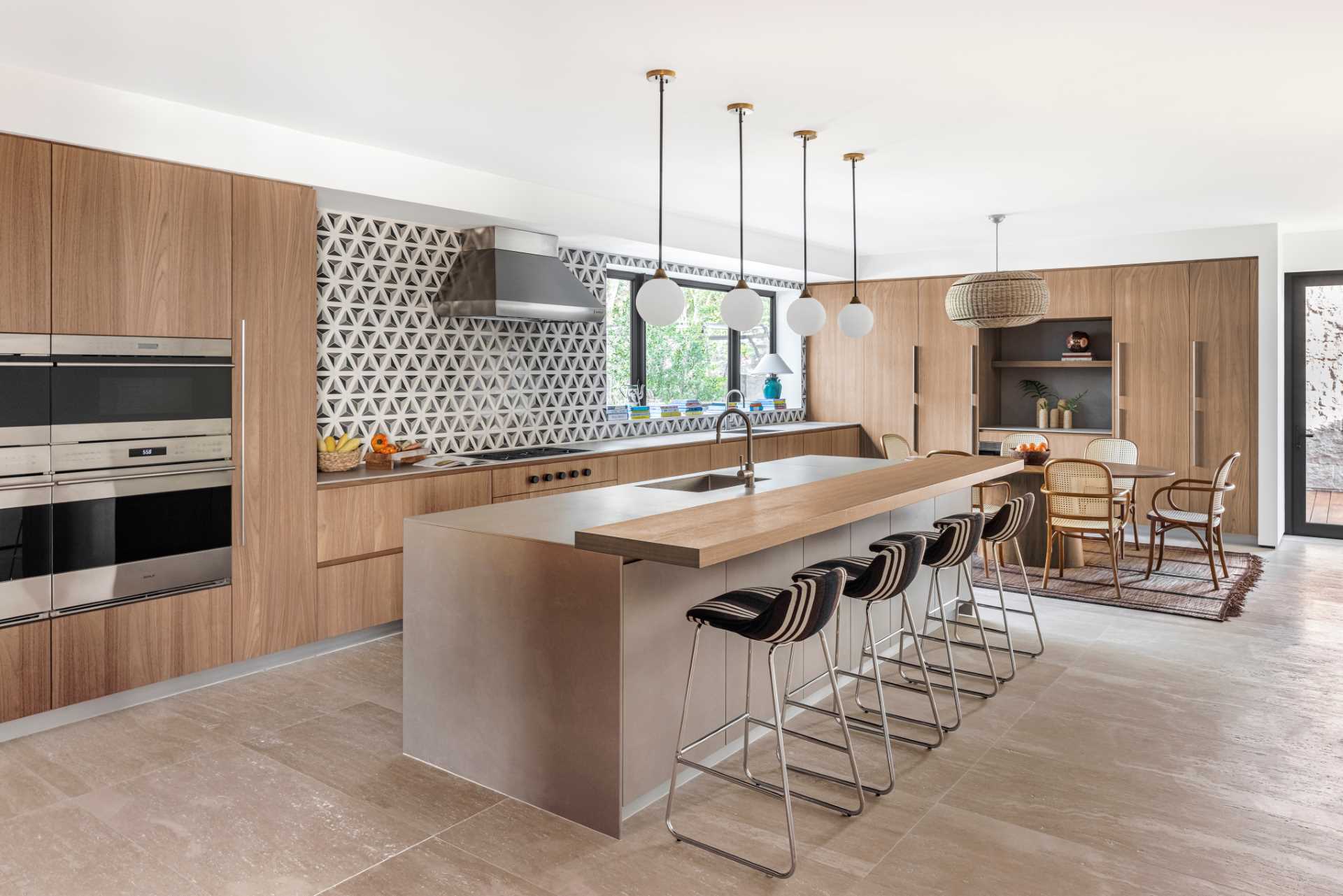 This modern kitchen, which features modern wood cabinets and a patterned backsplash, also includes a large island with counter stools. There's also a casual dining area.