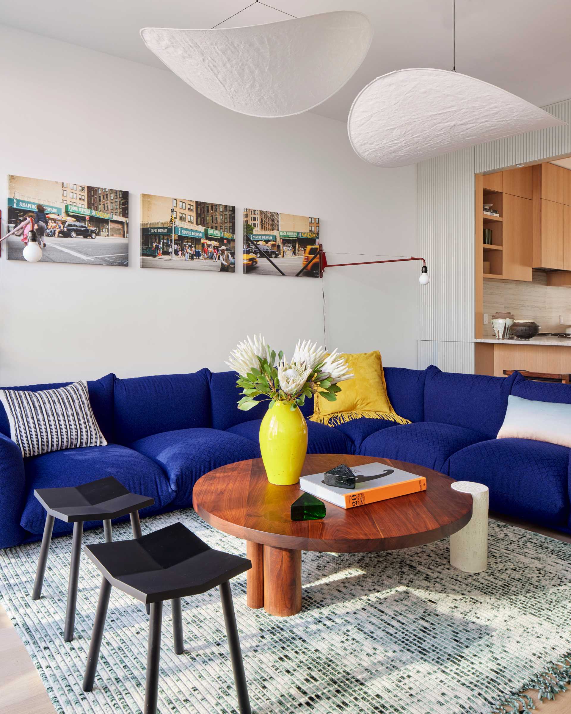 This modern living room looks out on the rear yard through floor-to-ceiling glass and includes a Marenco sectional in blue Kvadrat wool wraps, a coffee table by Hinterland Design, and a rug by Philippe Malouin.