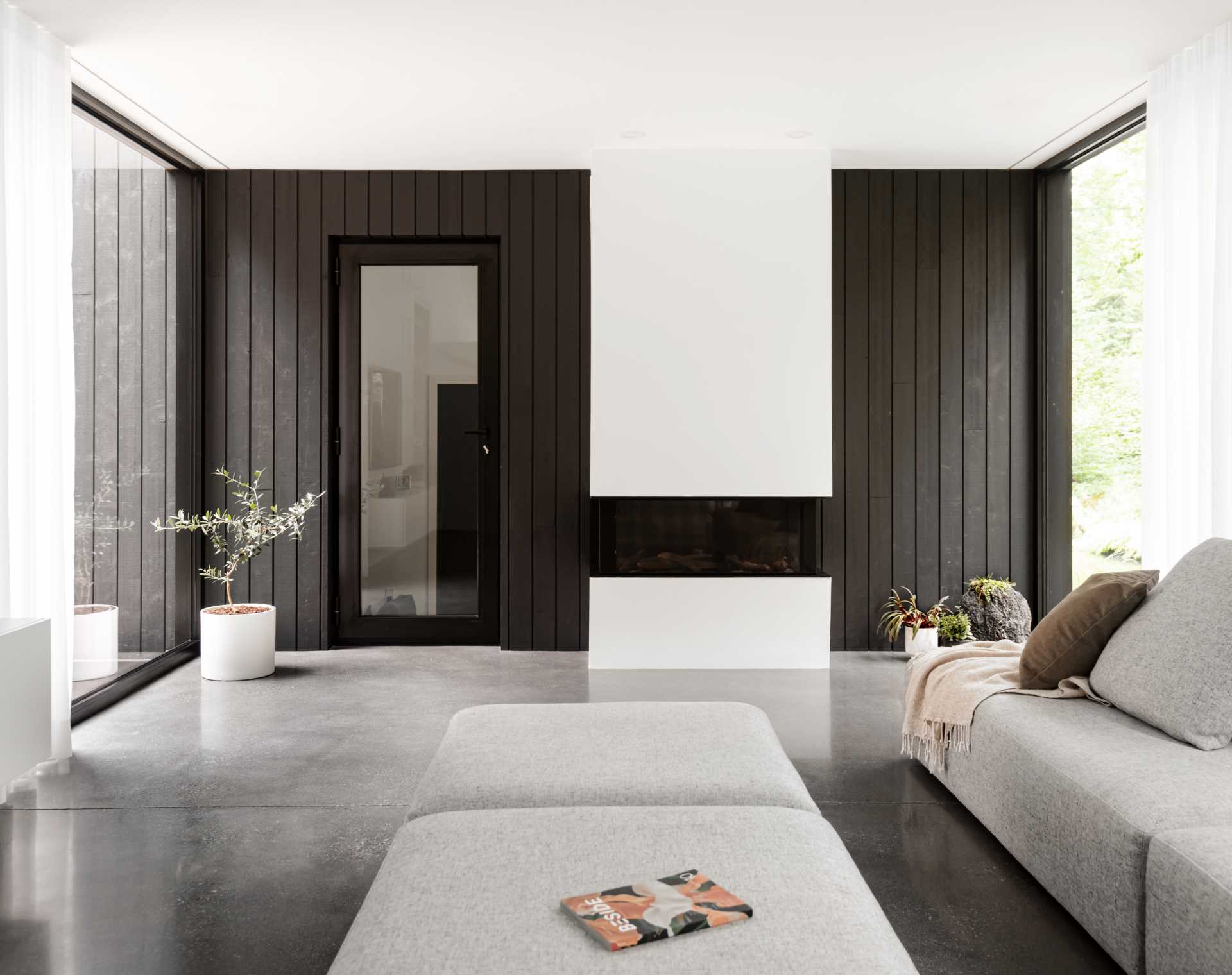 A modern home with polished concrete floors and black-framed picture windows.