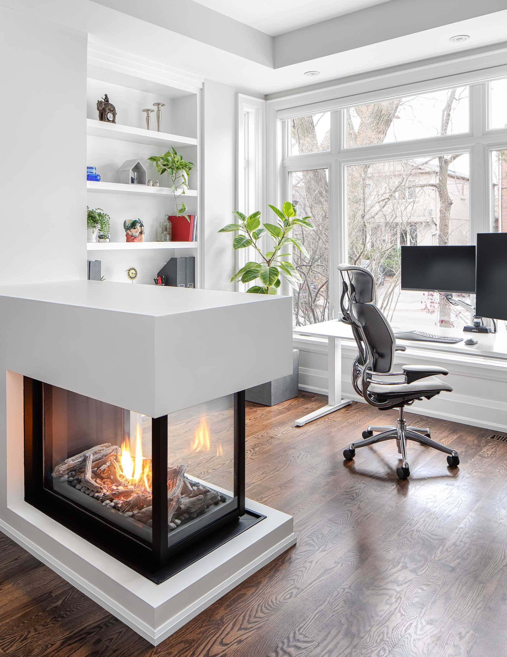 A low three-sided fireplace acts as a room divider separated the living room from the home office.