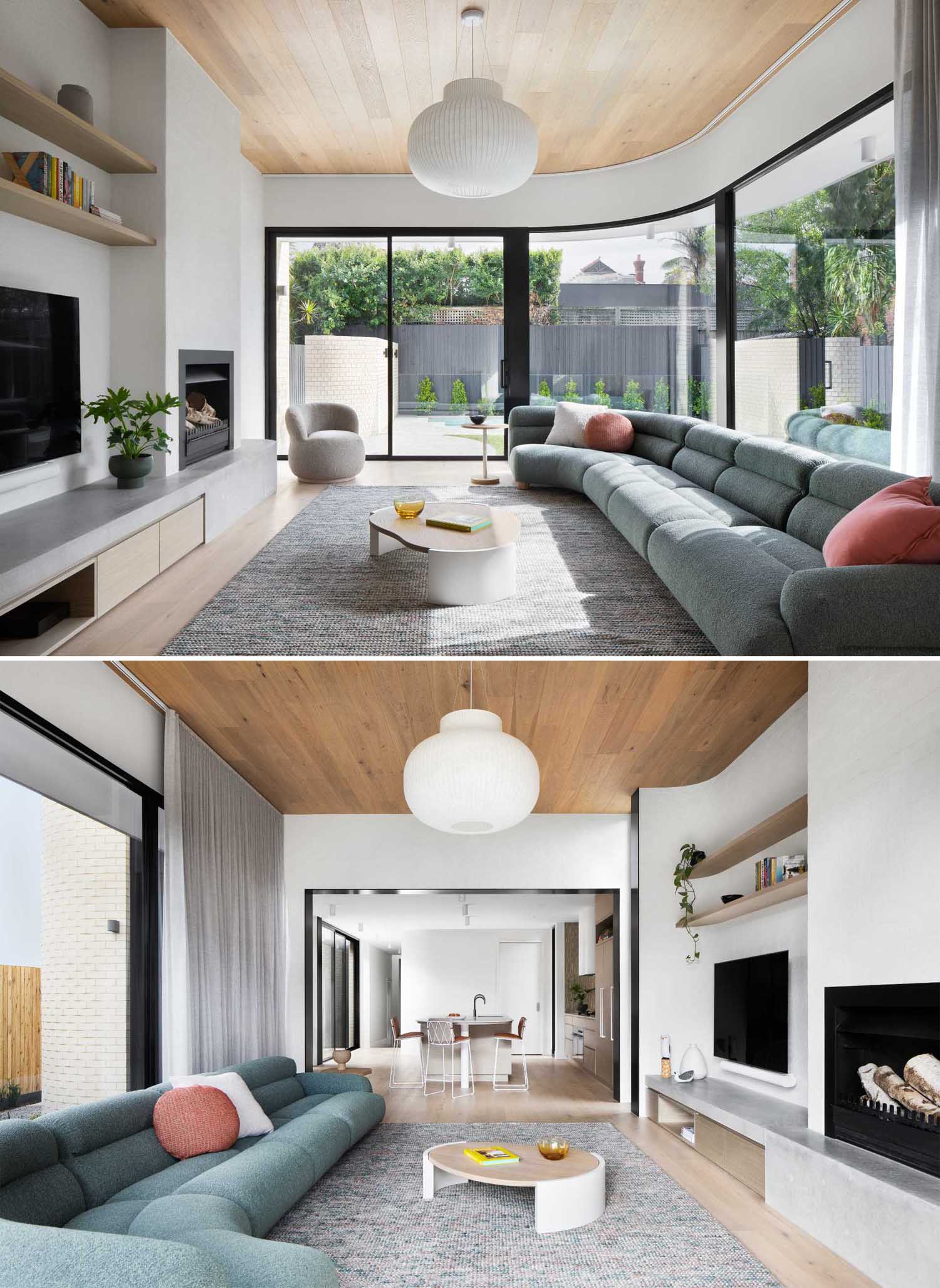 A modern living room with a curved wall, wood ceiling, fireplace, and a hearth that travels along the wall and includes a storage cabinet.