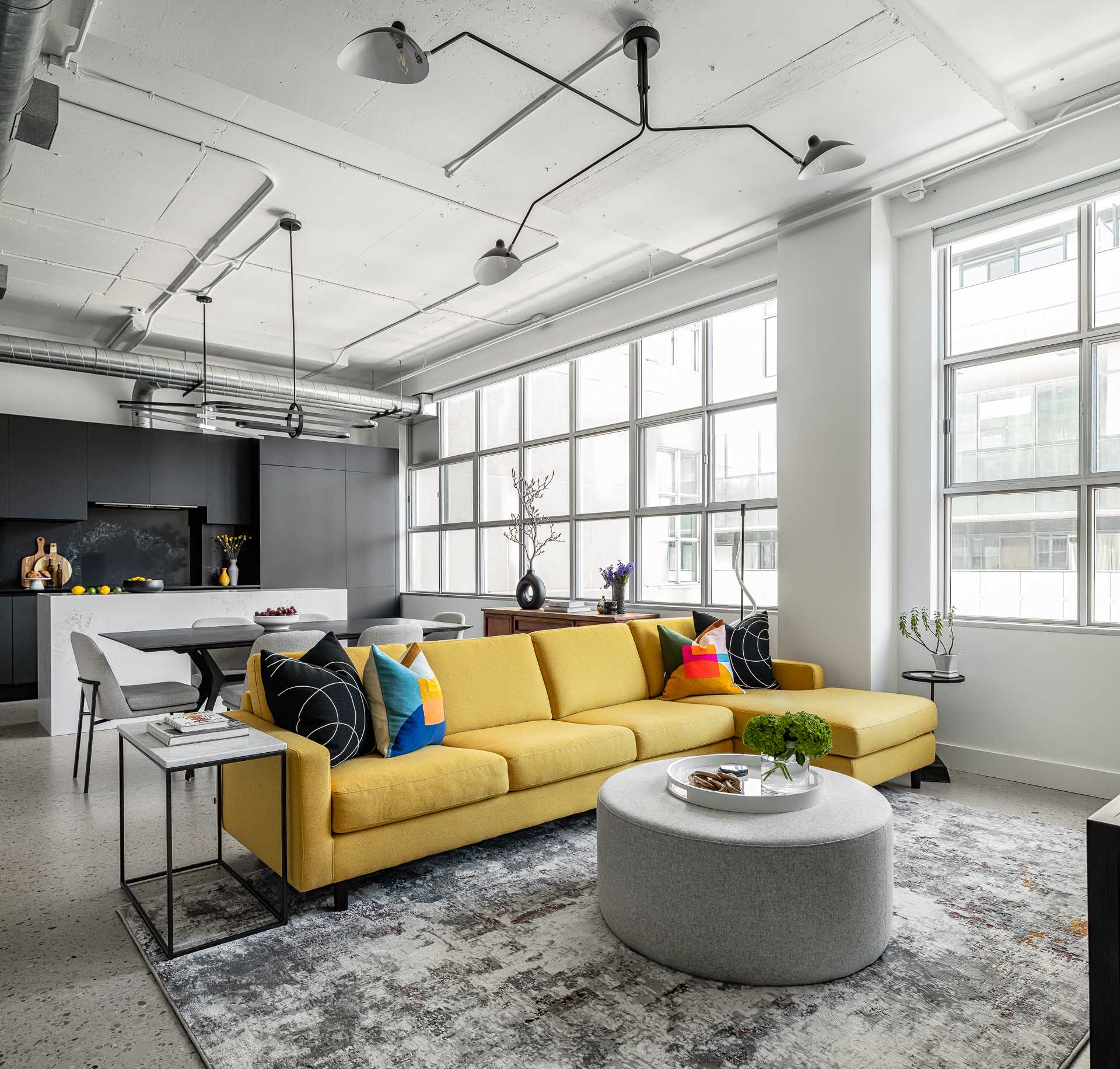 The living room in this modern loft apartment is home to a bright yellow sectional, as well as a large rug by Christoph Niemann.