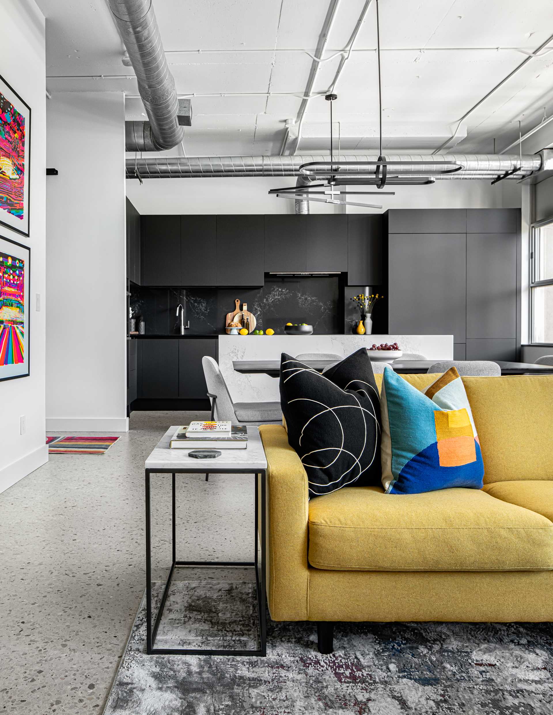 The living room in this modern loft apartment is home to a bright yellow sectional, as well as a large rug by Christoph Niemann.