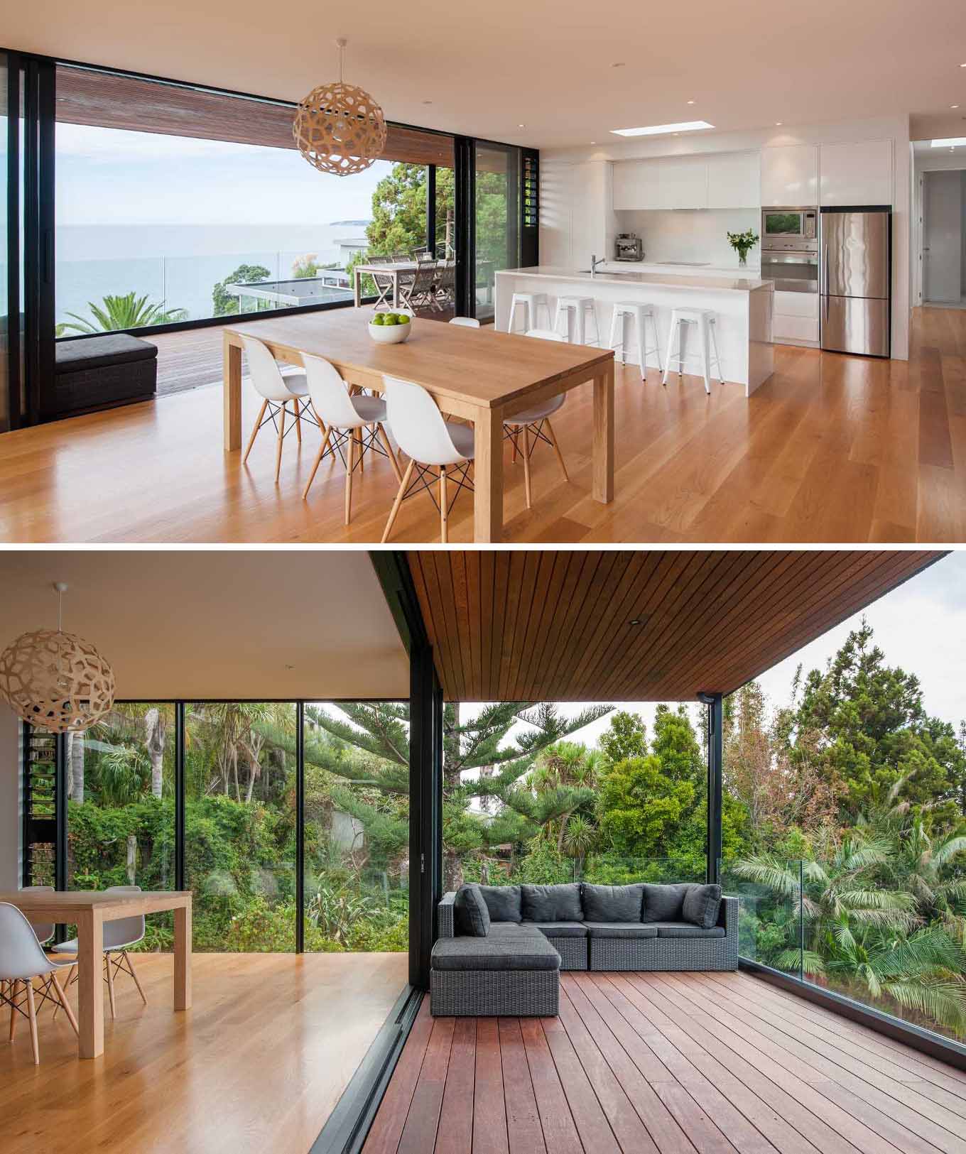 Inside this modern home, the main living areas are open-plan, with wood floors, and black-framed glass doors that open to extend the living space and provide access to the balcony and its uninterrupted water views.