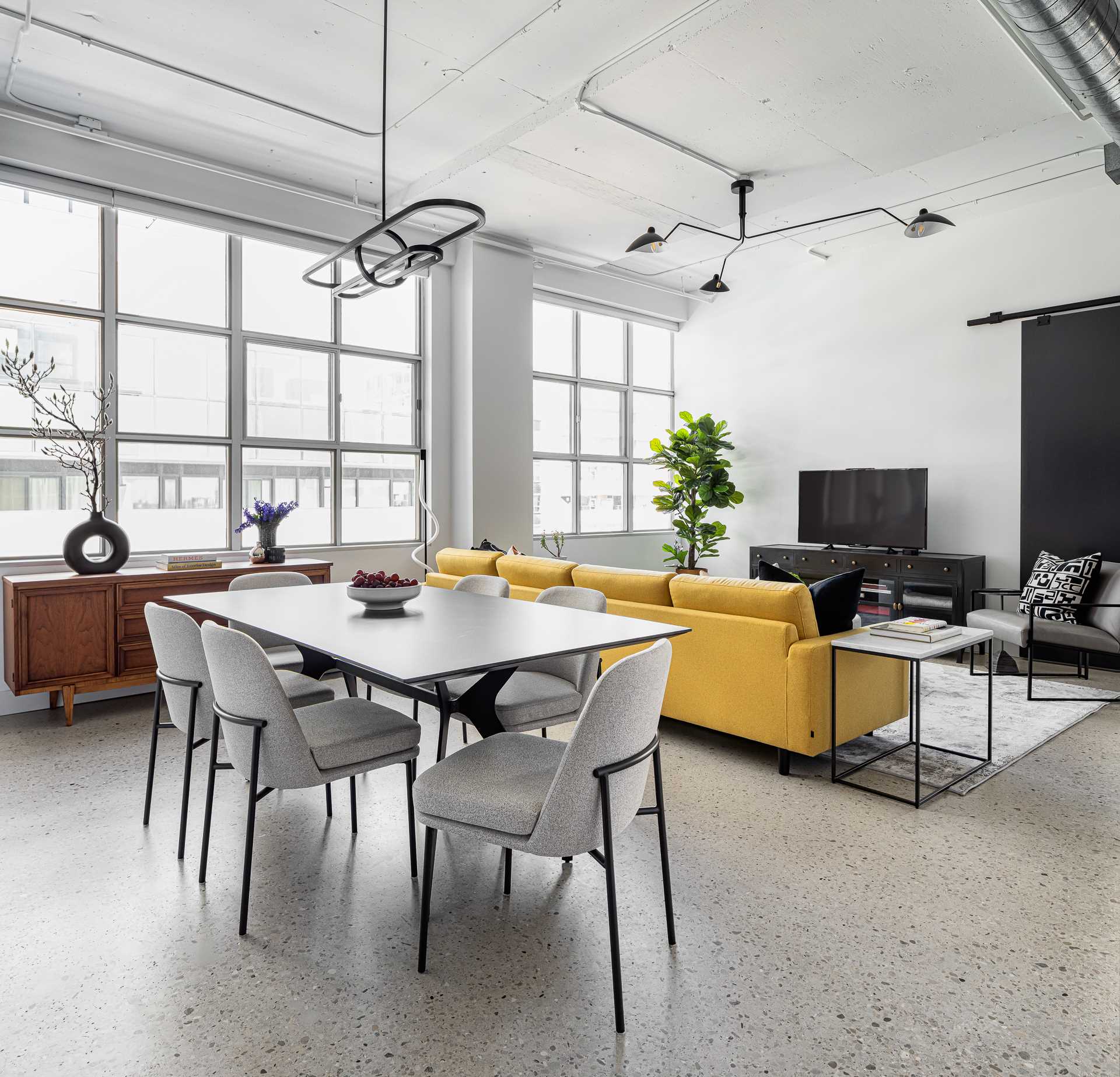 A trio of unique pendant lights that designate the kitchen, living, and dining areas in the open-concept loft.