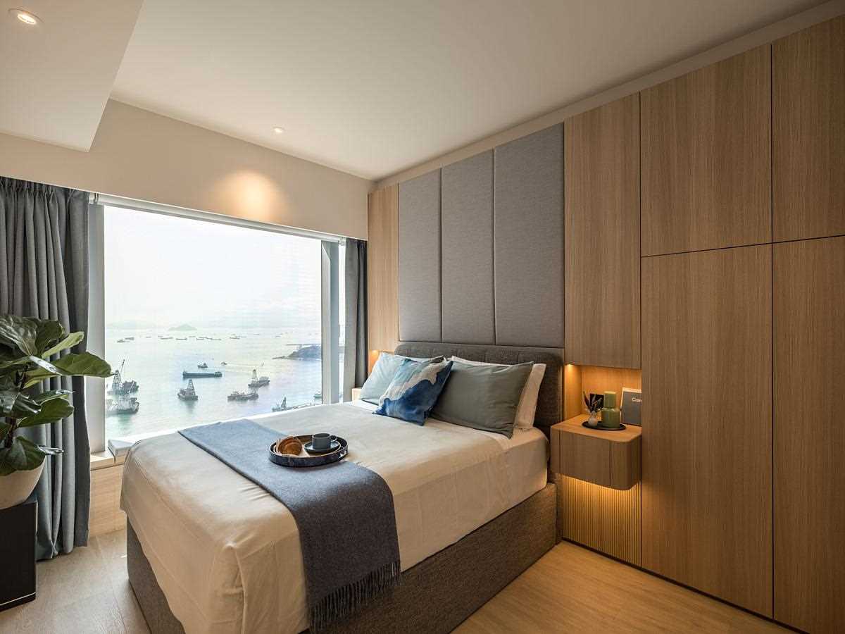 This modern primary bedroom includes wood accent walls, built-in bedside tables, hidden lighting, and frameless doors.