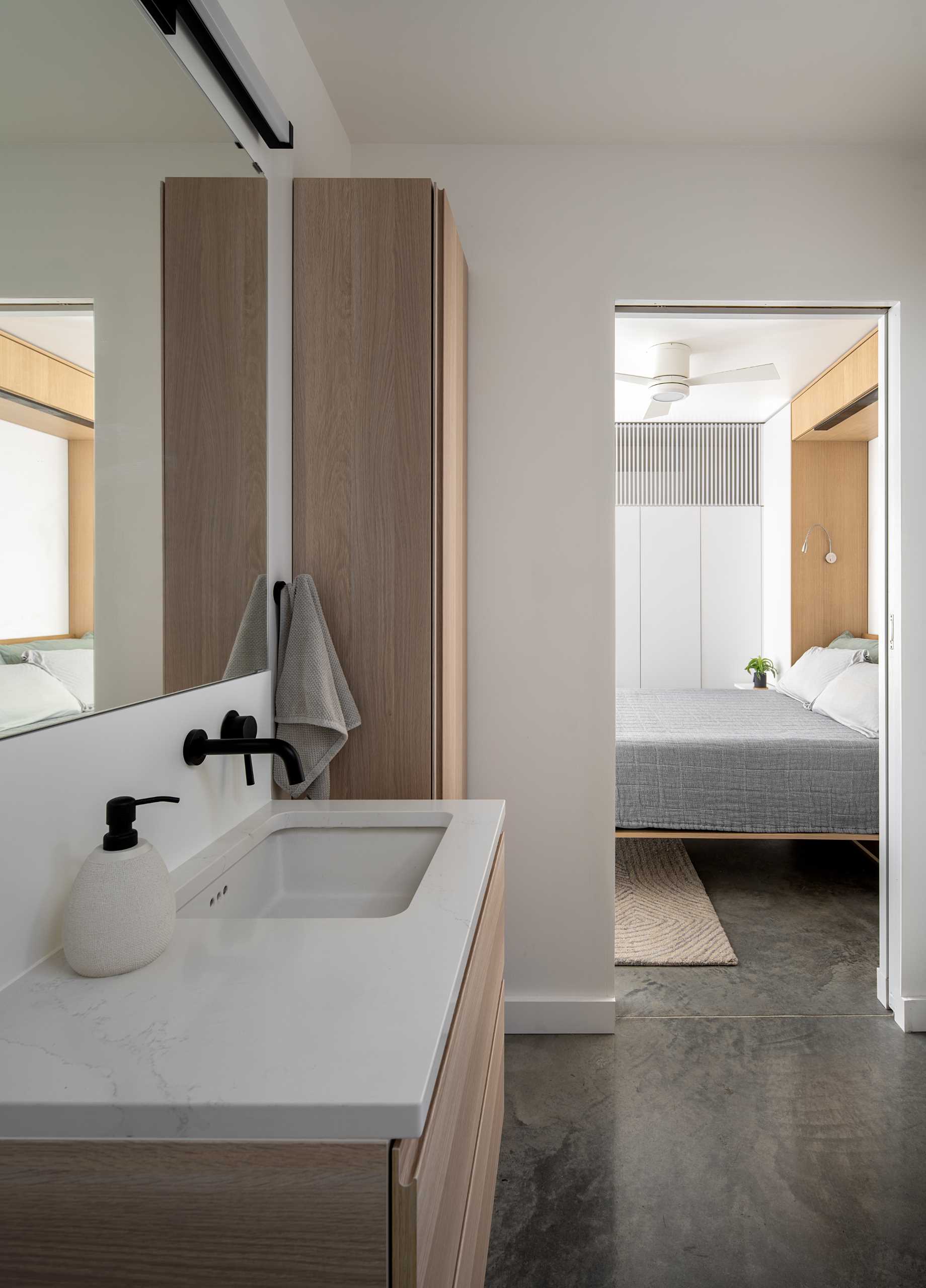 A modern en-suite bathroom with wood vanity and storage cabinet.